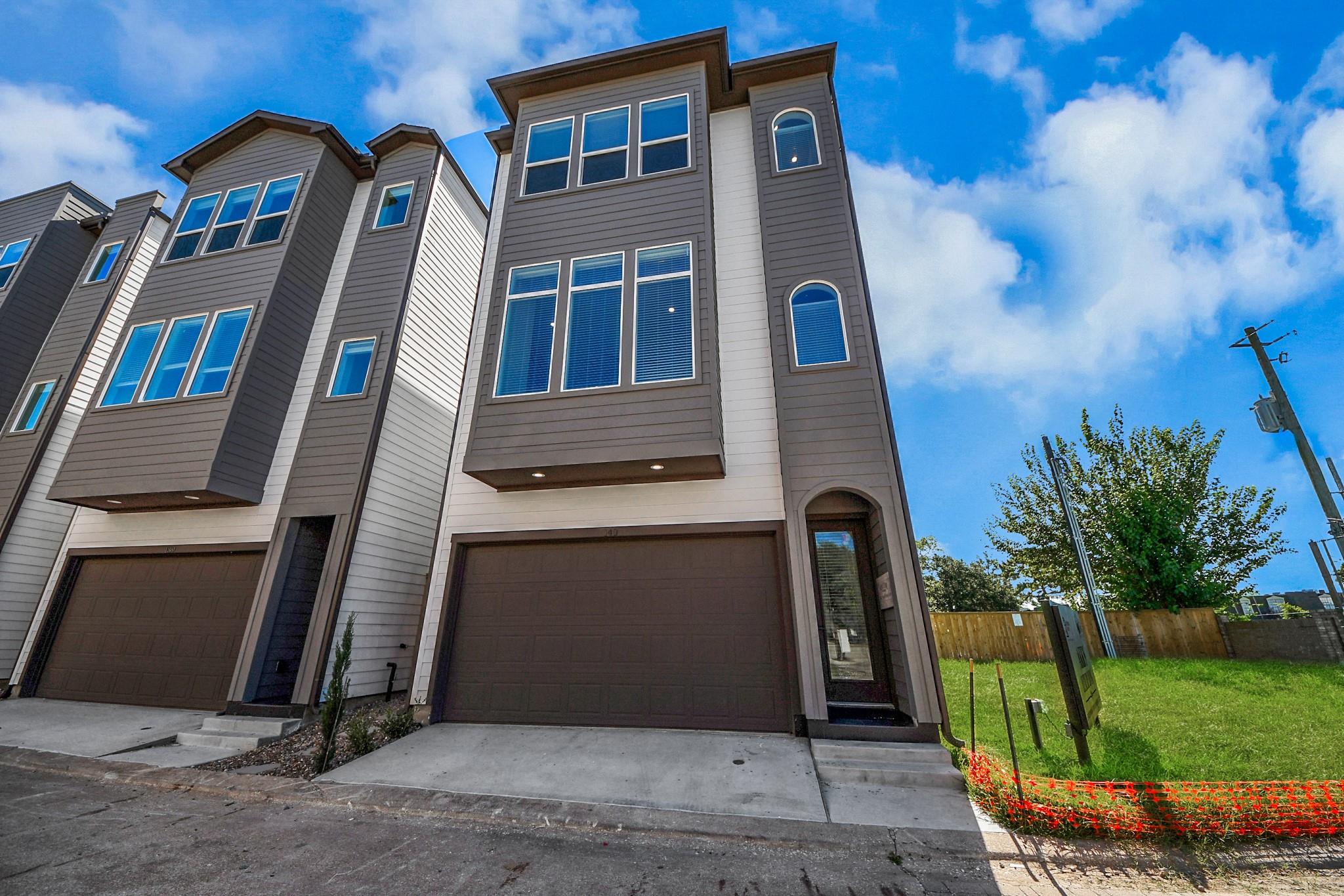 Three-story gray townhome with a two-car garage and recessed front entry.