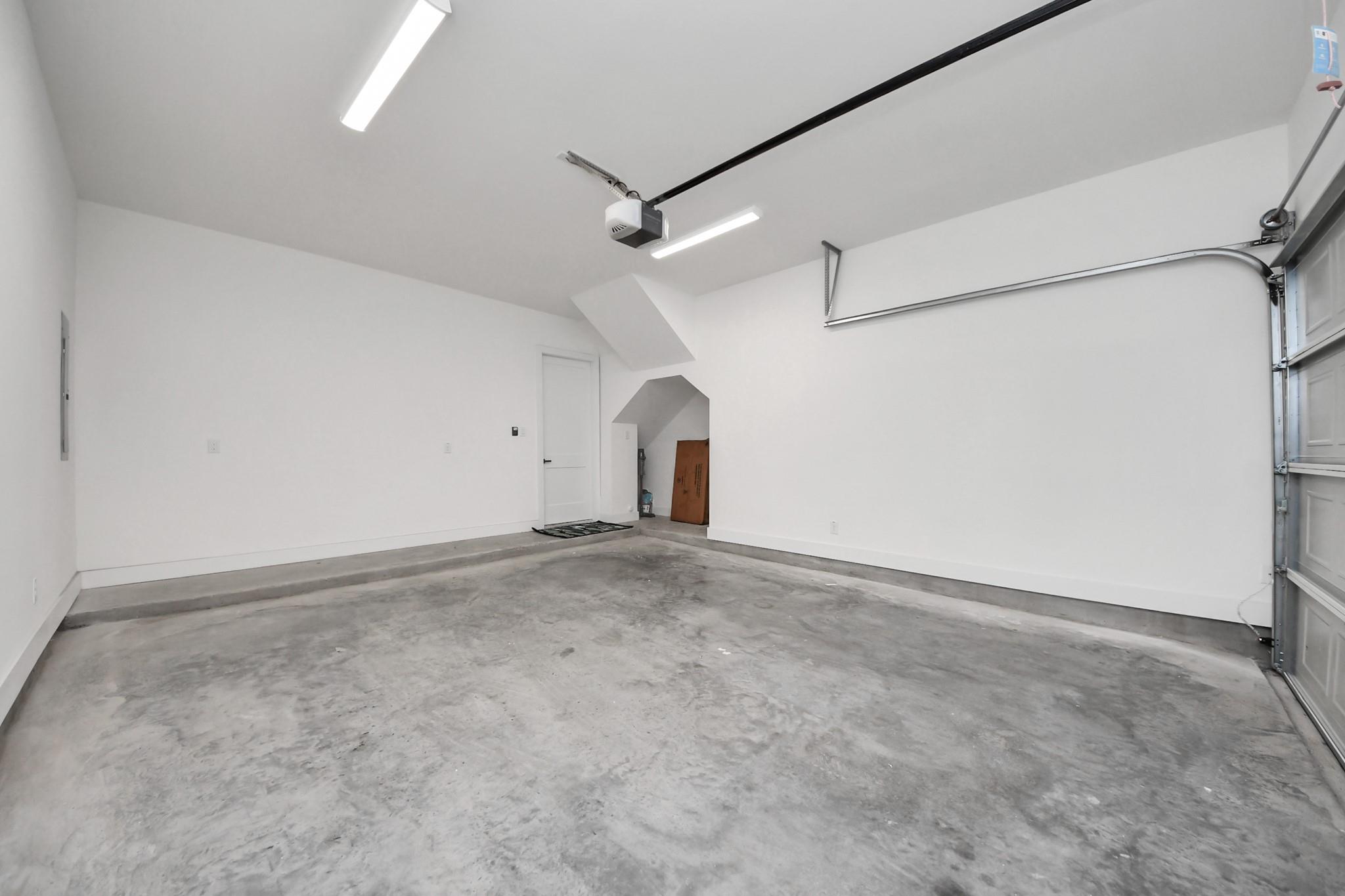 Empty garage with a concrete floor, overhead door, and small storage alcove.