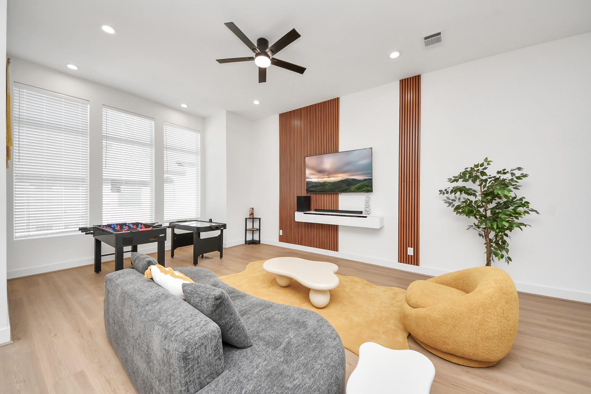 Furnished living and game room with a gray sectional, foosball table, and wood slat TV wall.