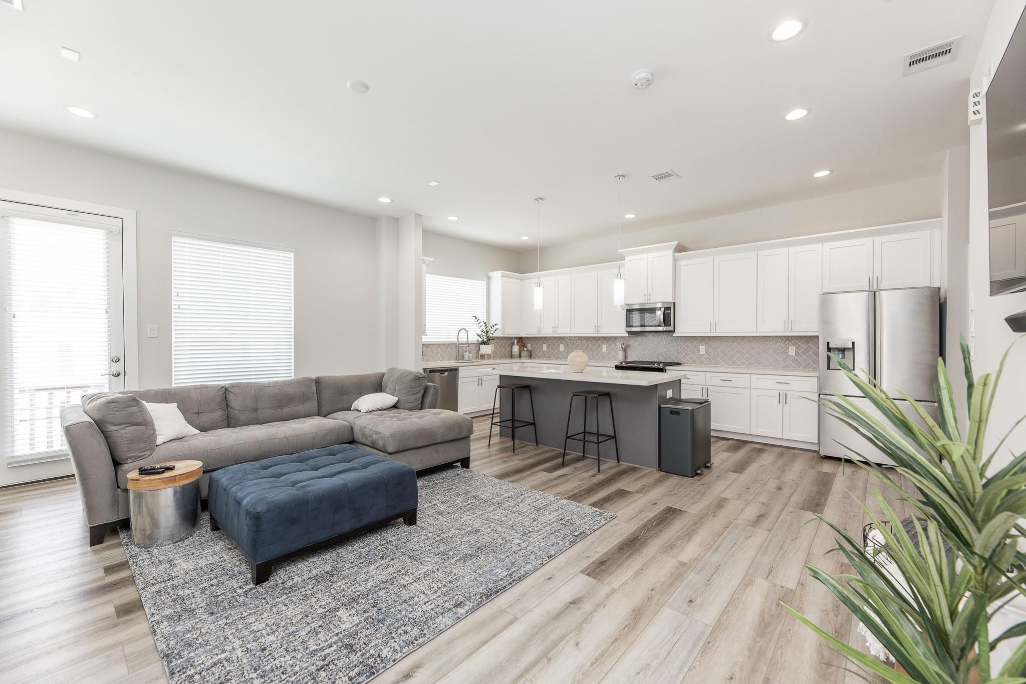 Open-plan living room and kitchen with a gray sectional and large island.