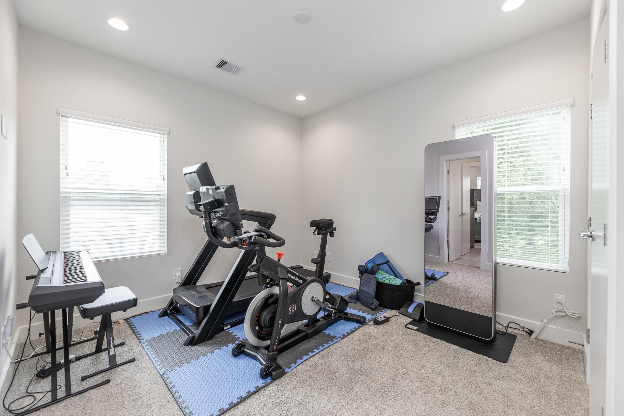 Home gym with a treadmill, stationary bike, keyboard, and large standing mirror.