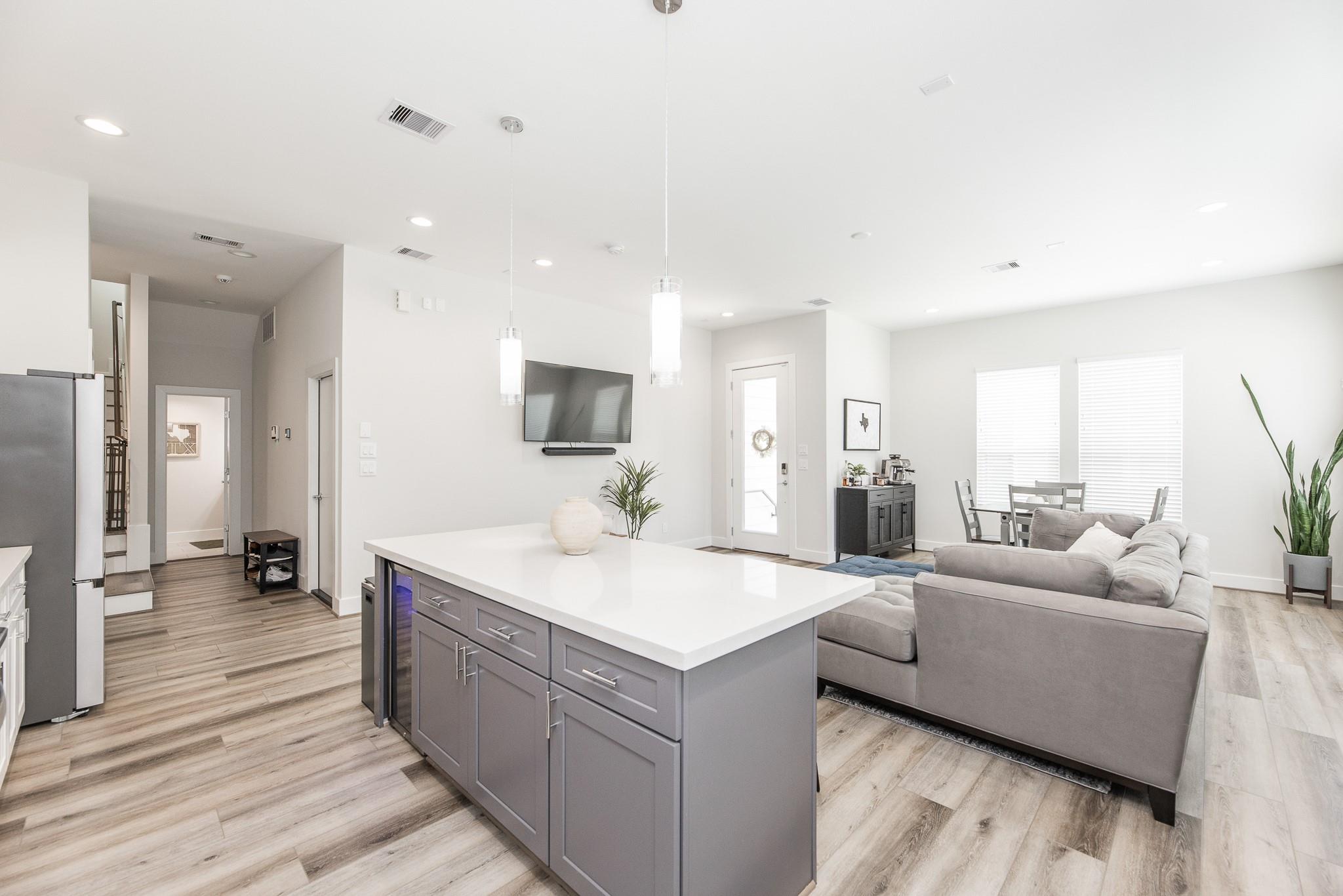 Open-plan kitchen and living room with a large gray island and gray sectional sofa.