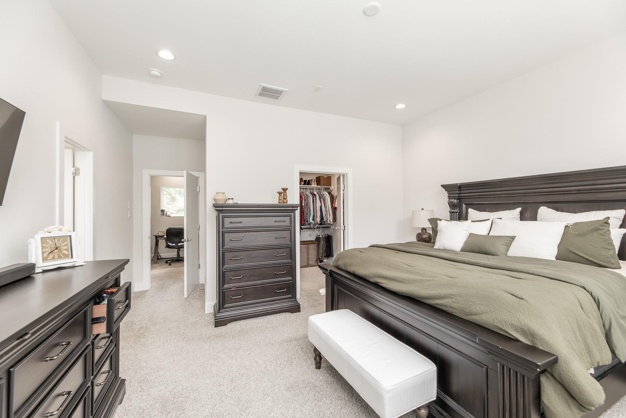 Bedroom with a dark wood bed and matching dressers, open closet, and doorway to an office.
