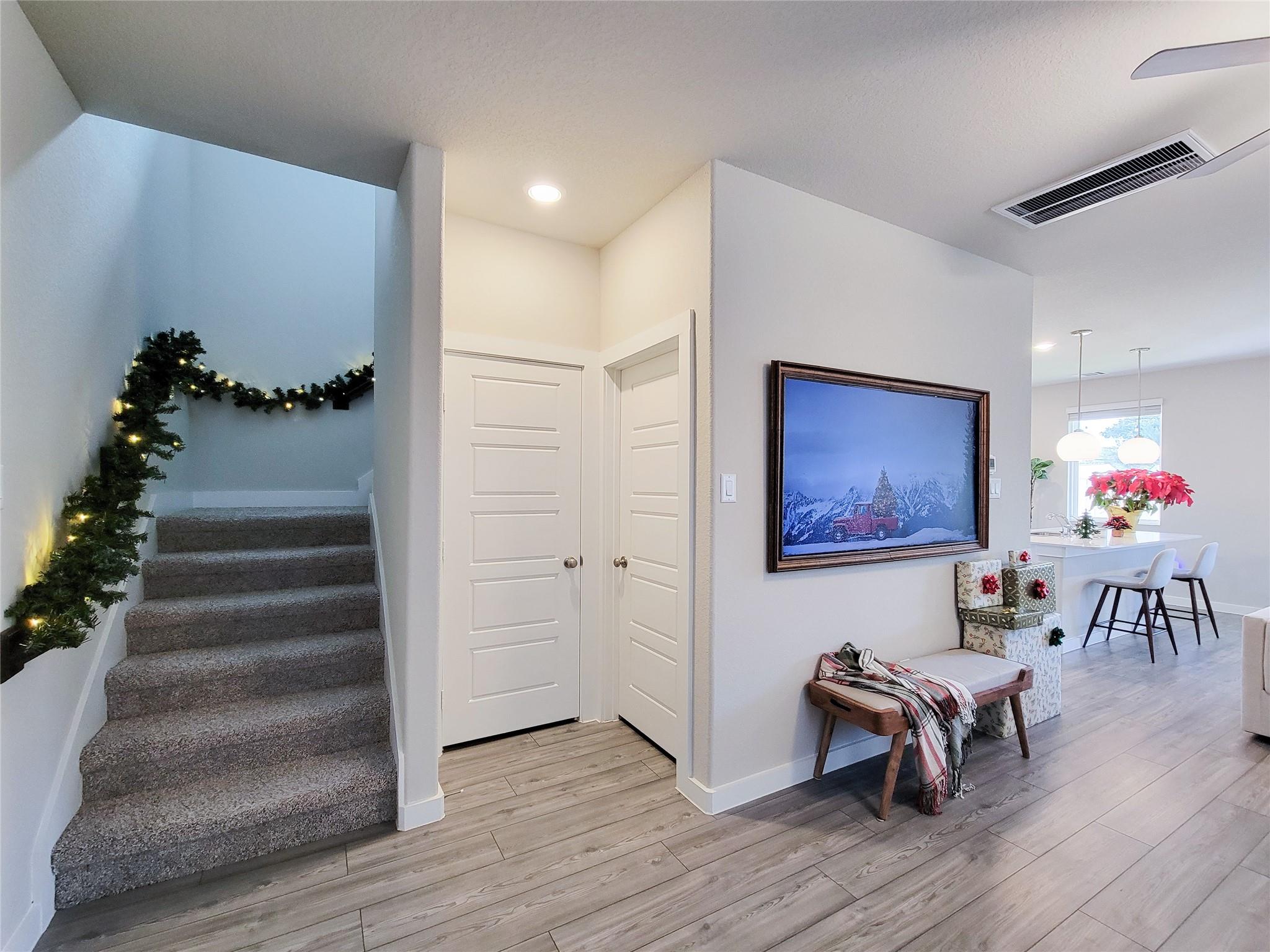 Furnished entryway with carpeted stairs, holiday garland, white paneled doors, and an adjoining dining area.