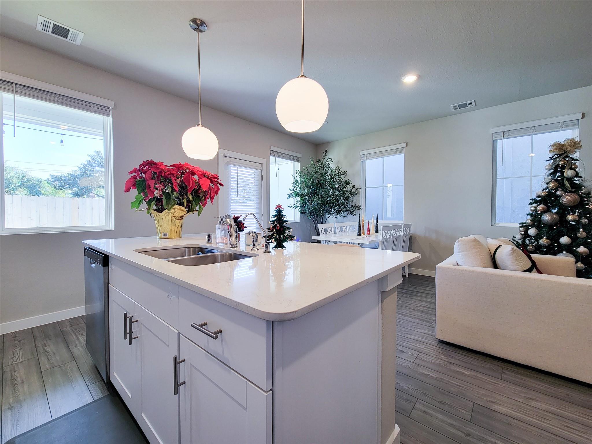 Open kitchen with a large white island, pendant lights, dining area, and decorated Christmas tree.