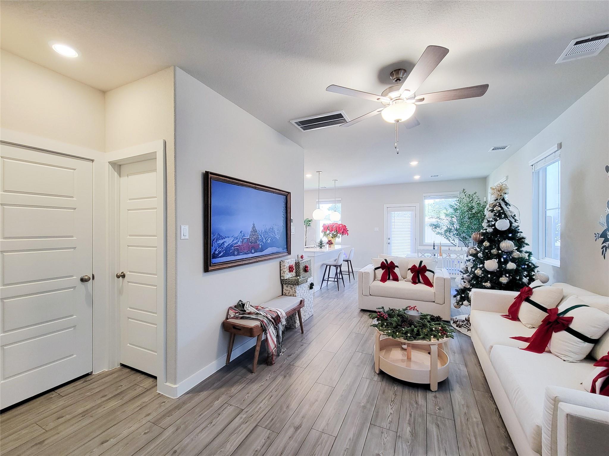 Open-plan living room with white sofas, red bows, and a decorated Christmas tree.