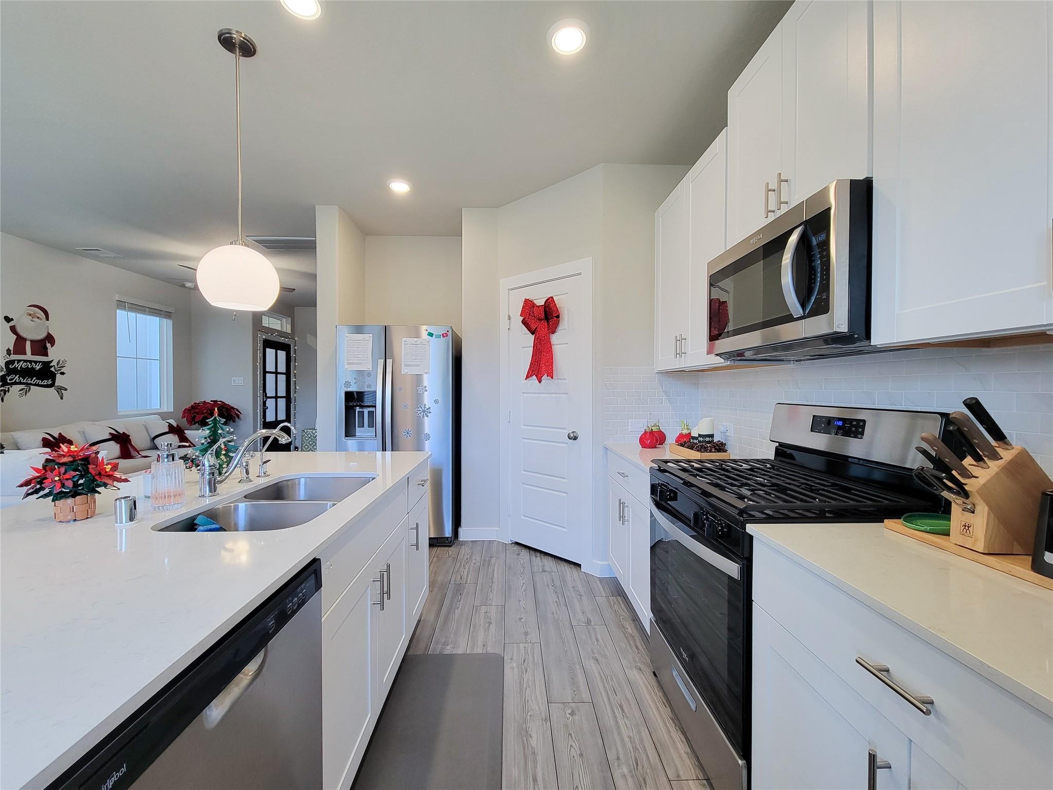 Bright white kitchen with a large island, stainless steel appliances, and Christmas decorations.