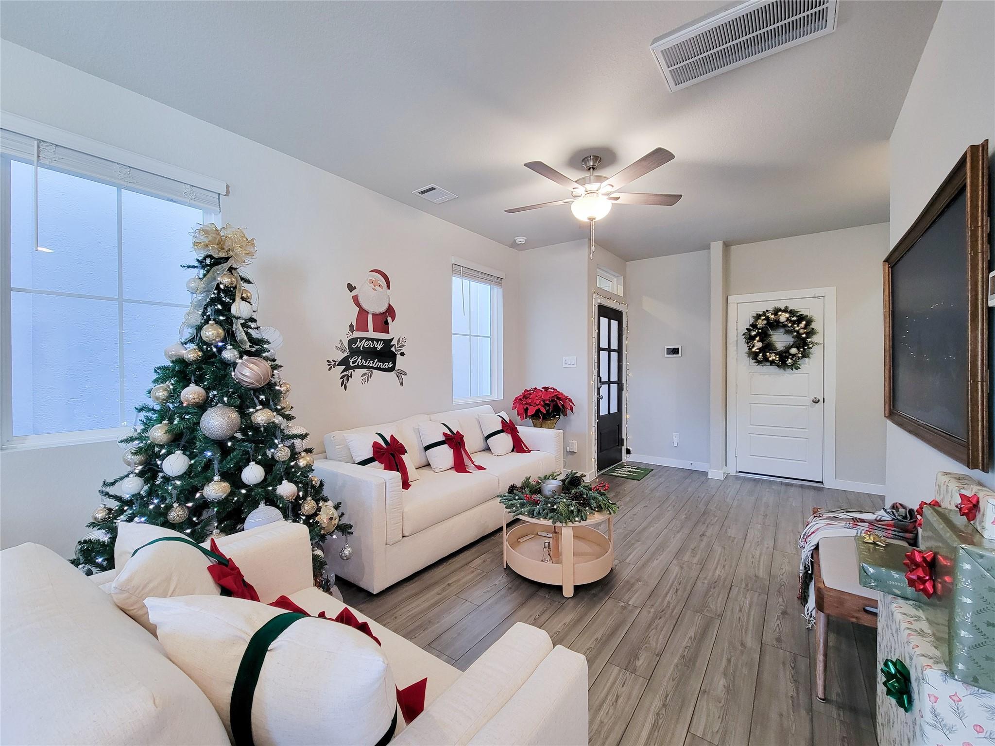 Living room with white sofas, a decorated Christmas tree, and festive red accents.