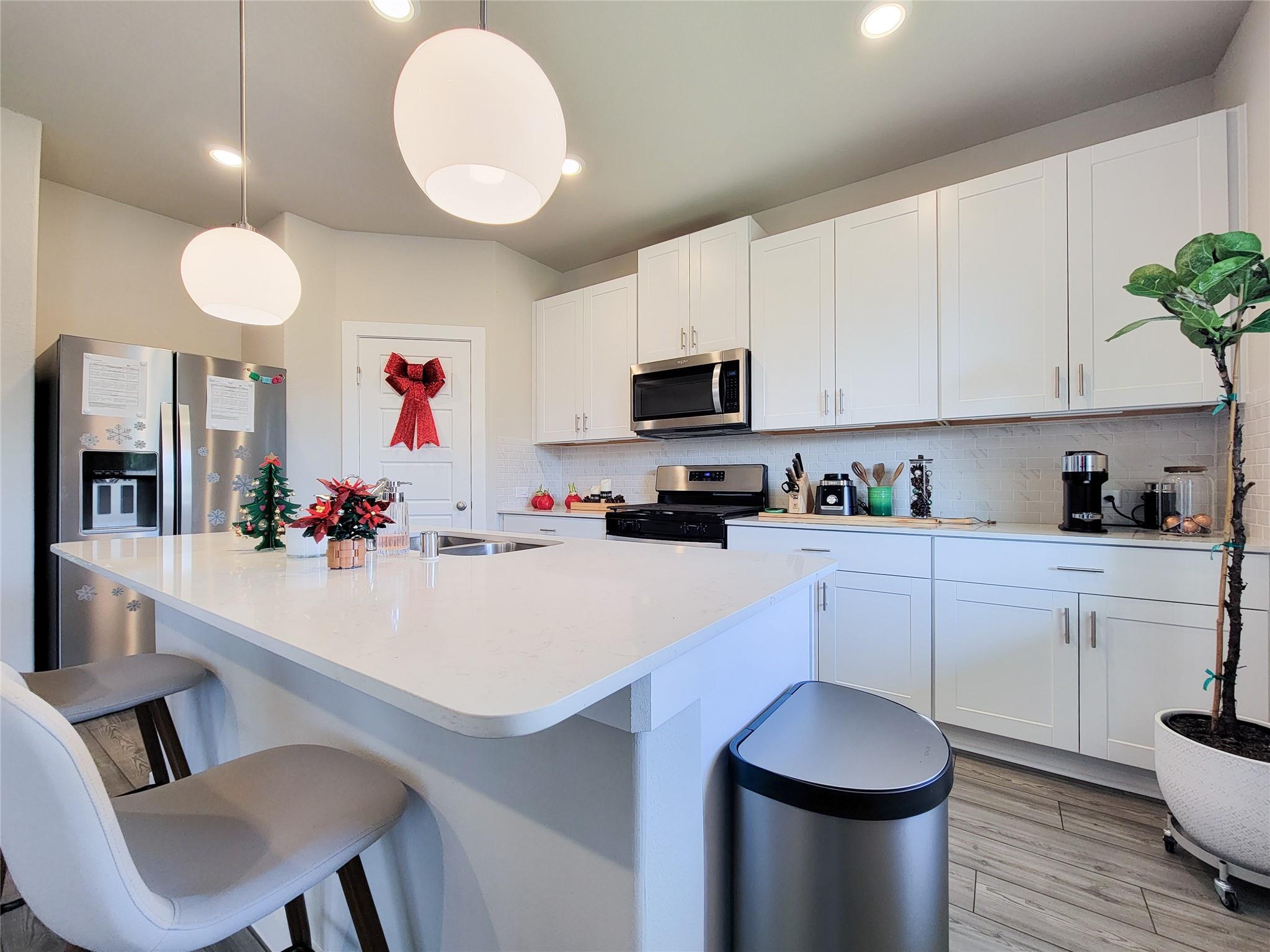 Kitchen with white cabinets, a large island, stainless steel appliances, and Christmas decorations.