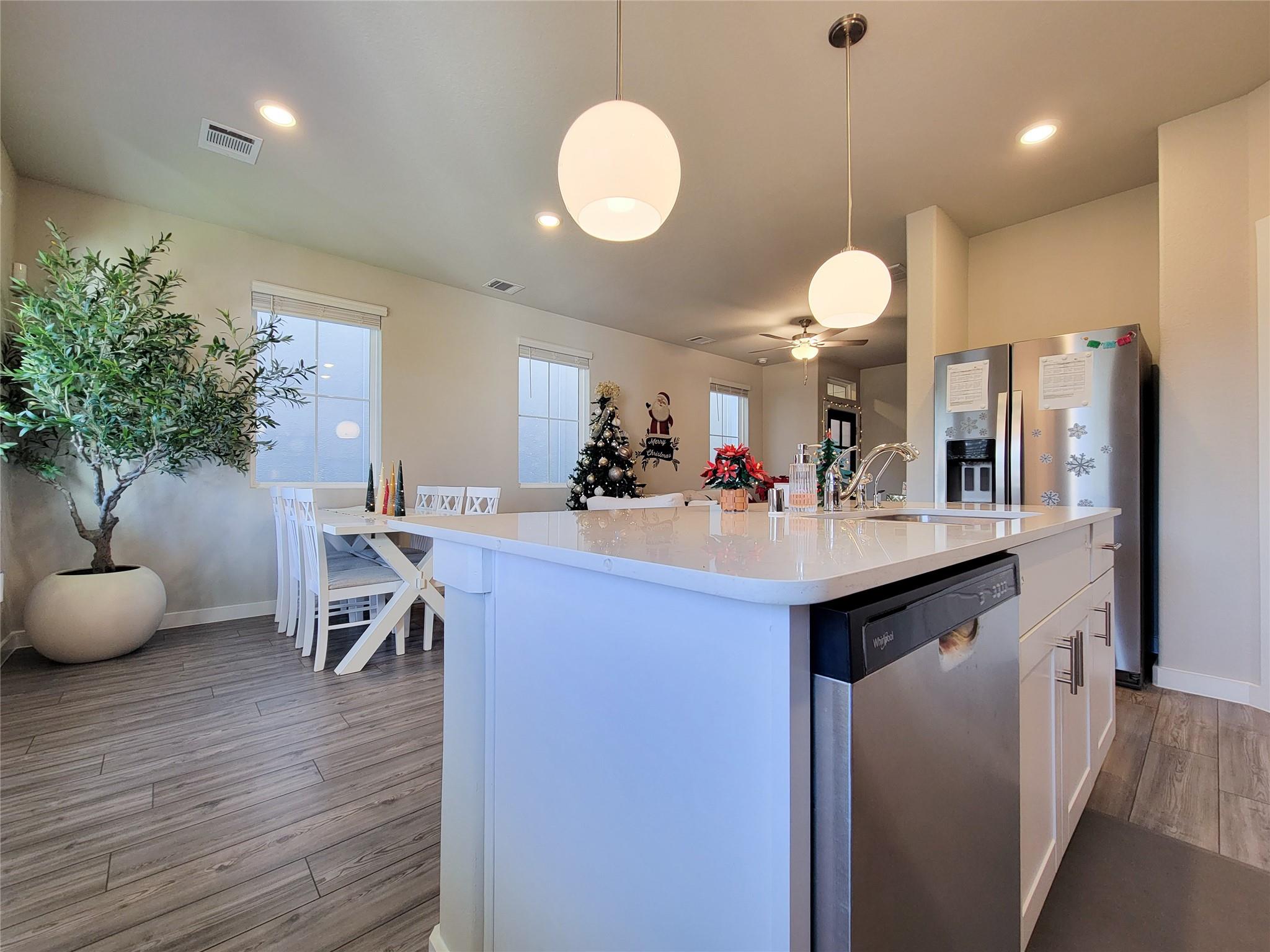 Open kitchen and dining area with a large white island, pendant lights, and Christmas decorations.