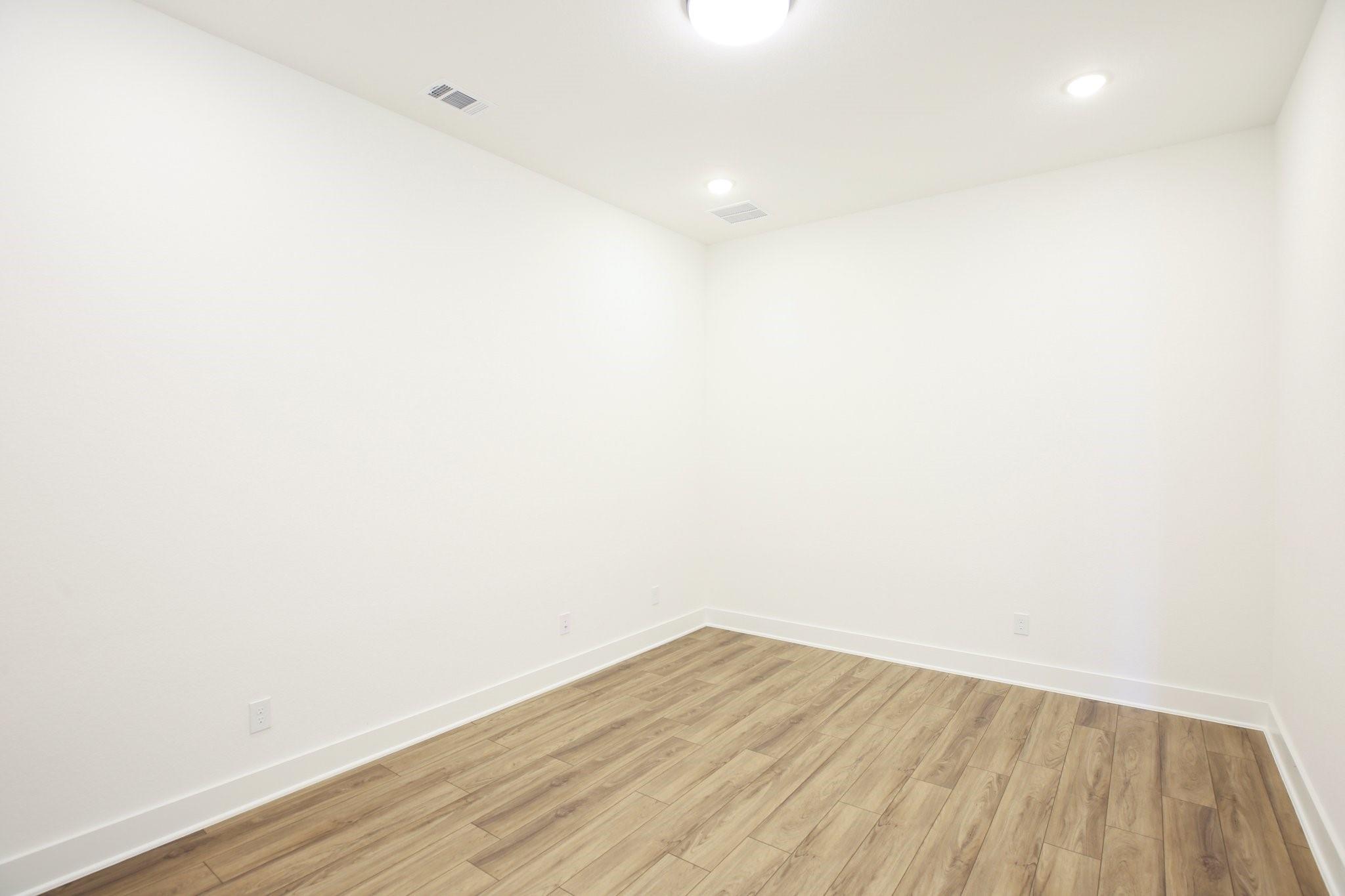 Empty room with light wood-look plank flooring and white walls.
