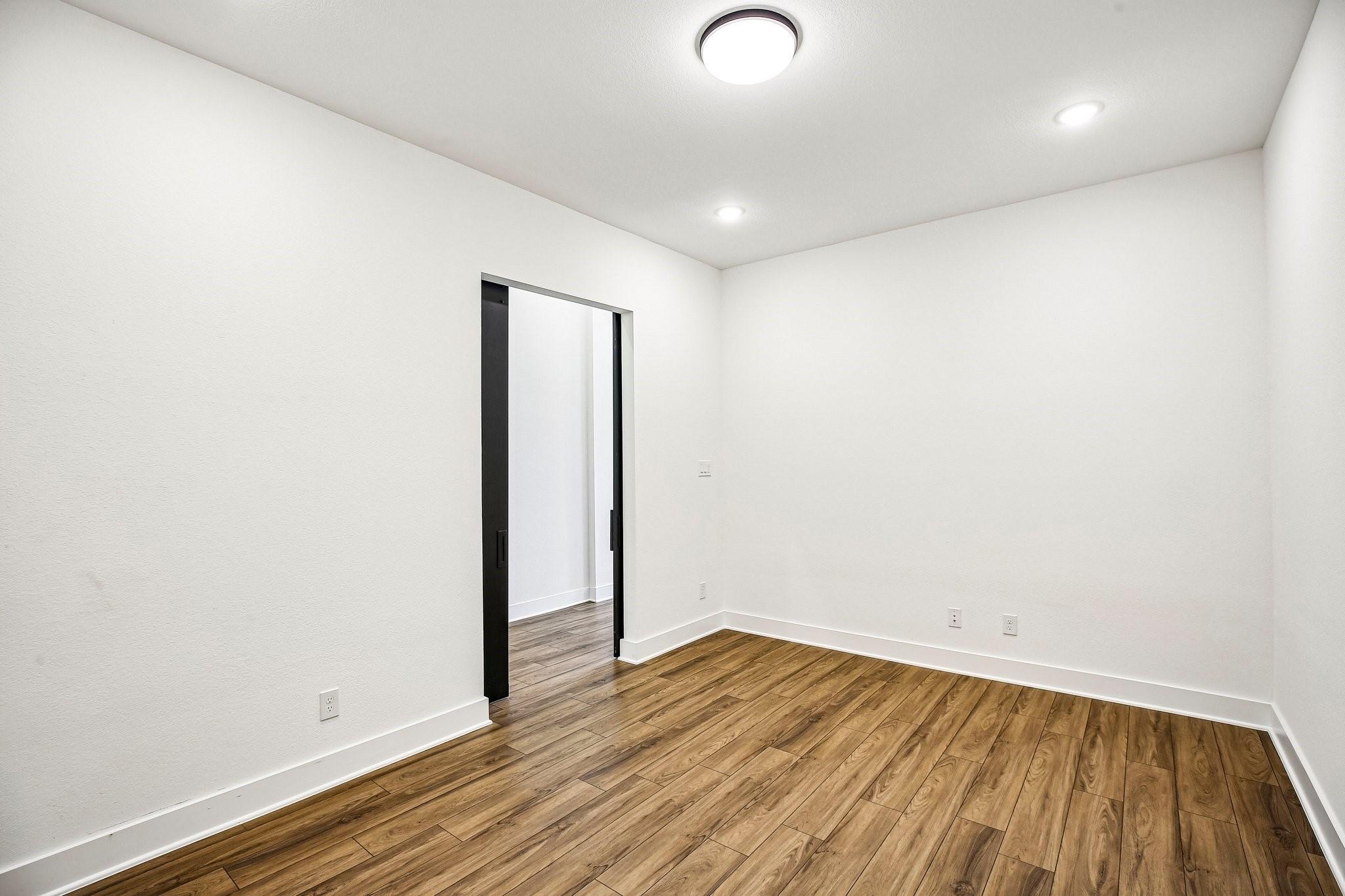 Empty room with wood-look flooring and a black-framed sliding doorway.