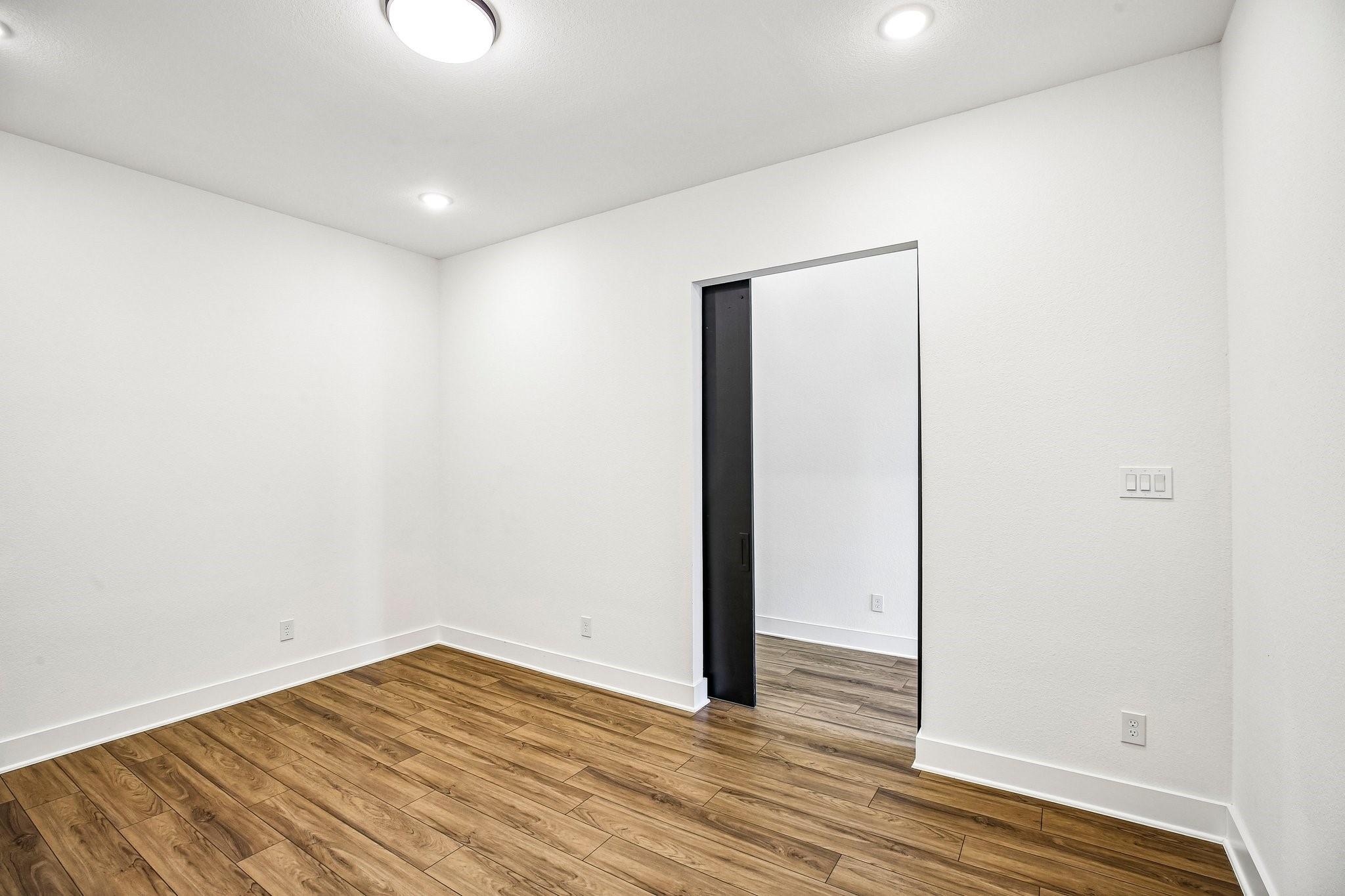 Empty room with wood-look flooring and an open doorway.