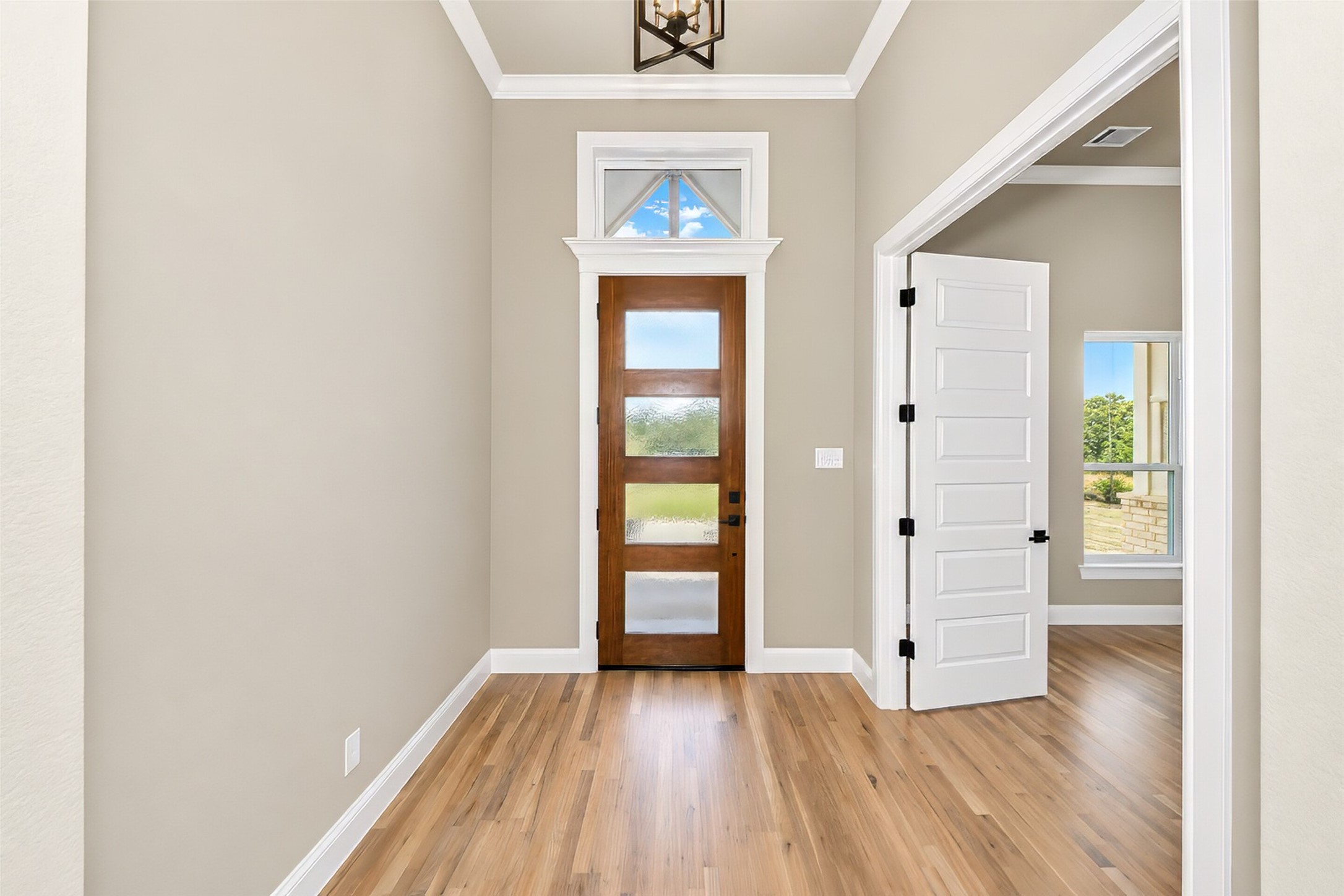 Entry foyer with a wood-and-frosted-glass front door, high ceiling, and hardwood floors.