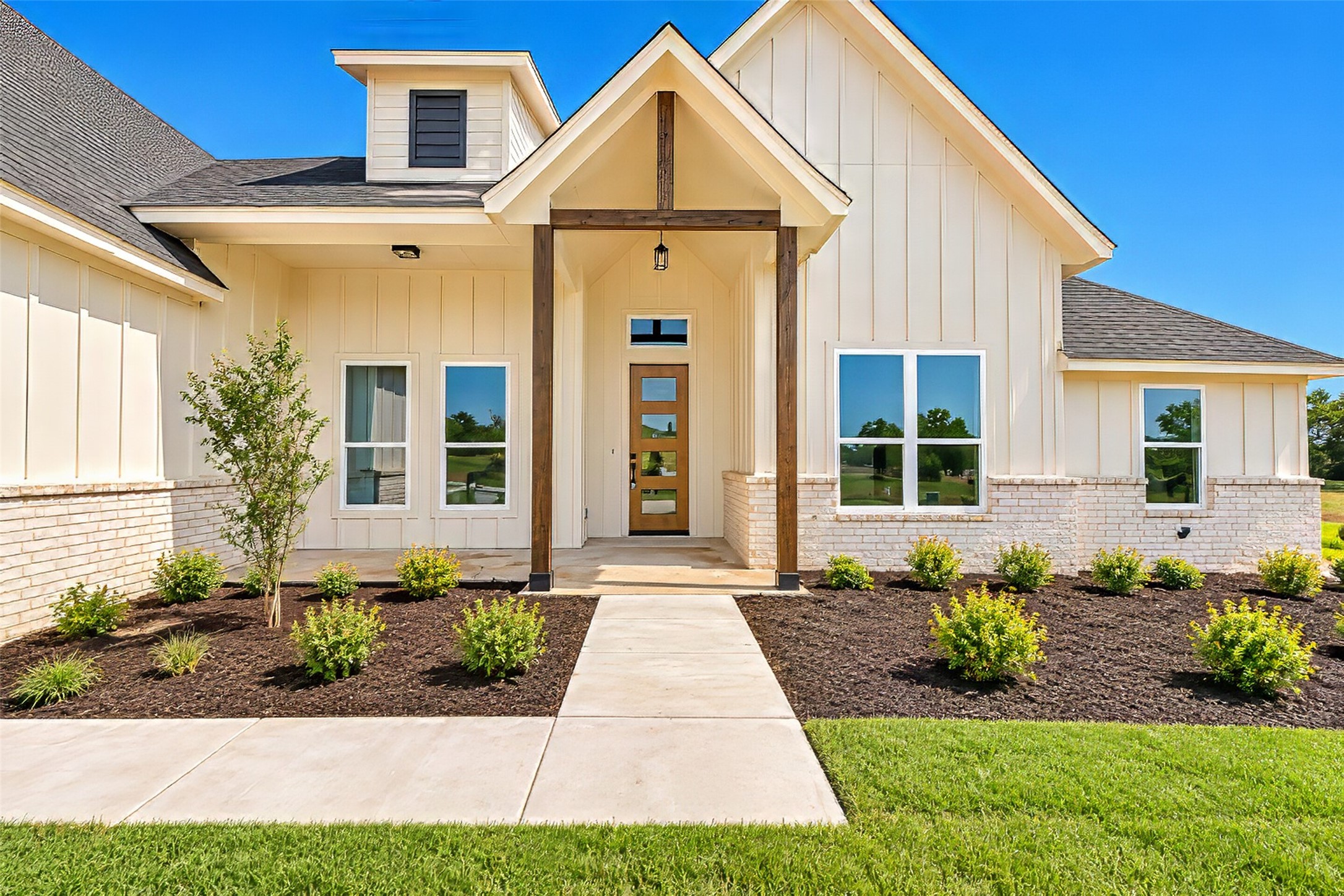 Home exterior with a covered timber-post entry, white brick base, and landscaped front walkway.