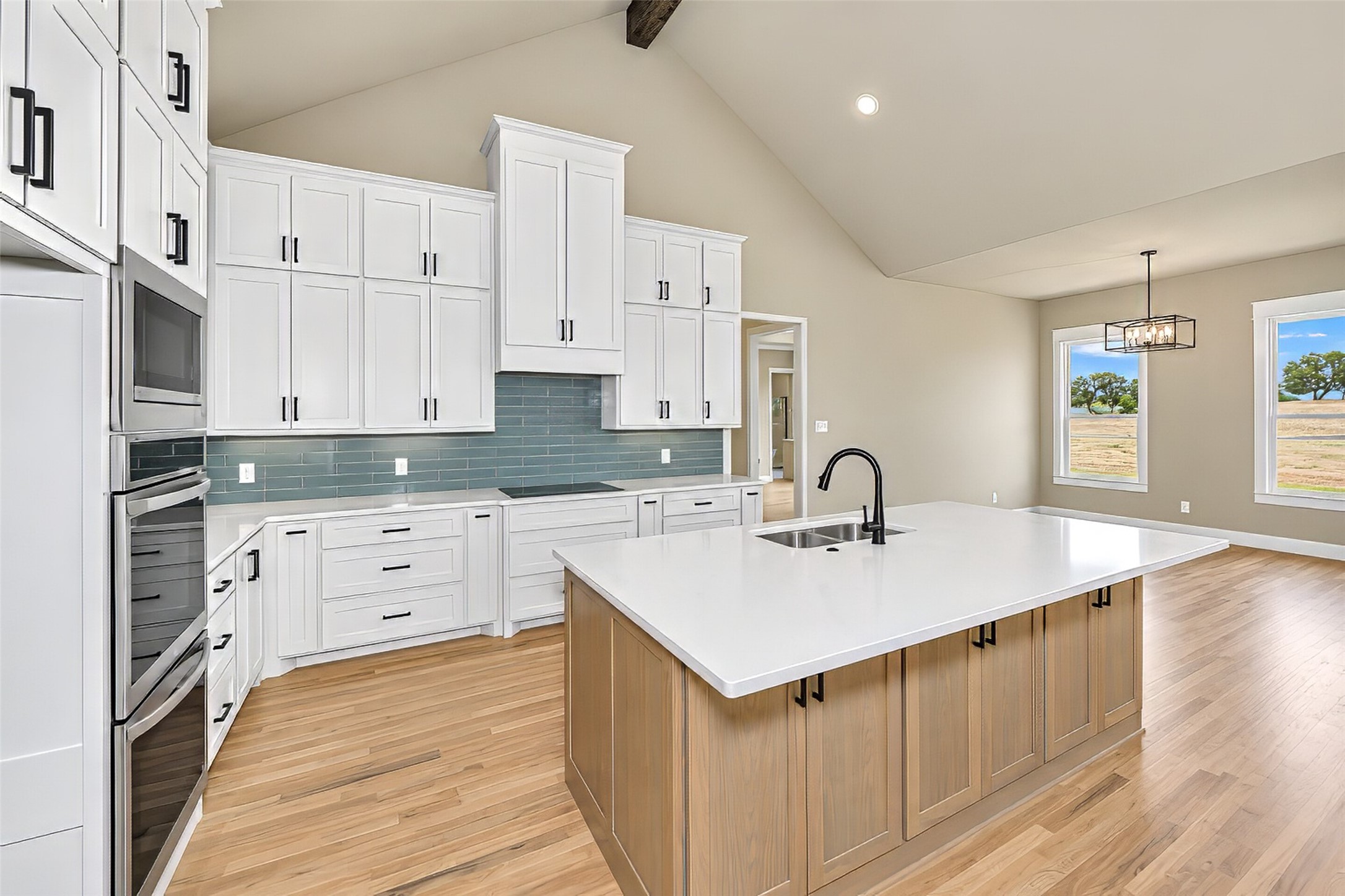 Kitchen with white cabinets, blue-gray tile backsplash, and a large wood-paneled island.