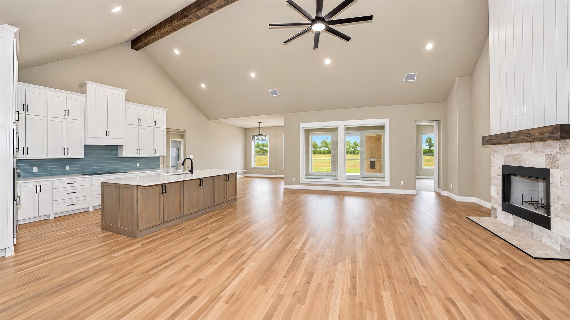 Open-plan kitchen and living area with a wood-paneled island, hardwood floors, and stone fireplace.