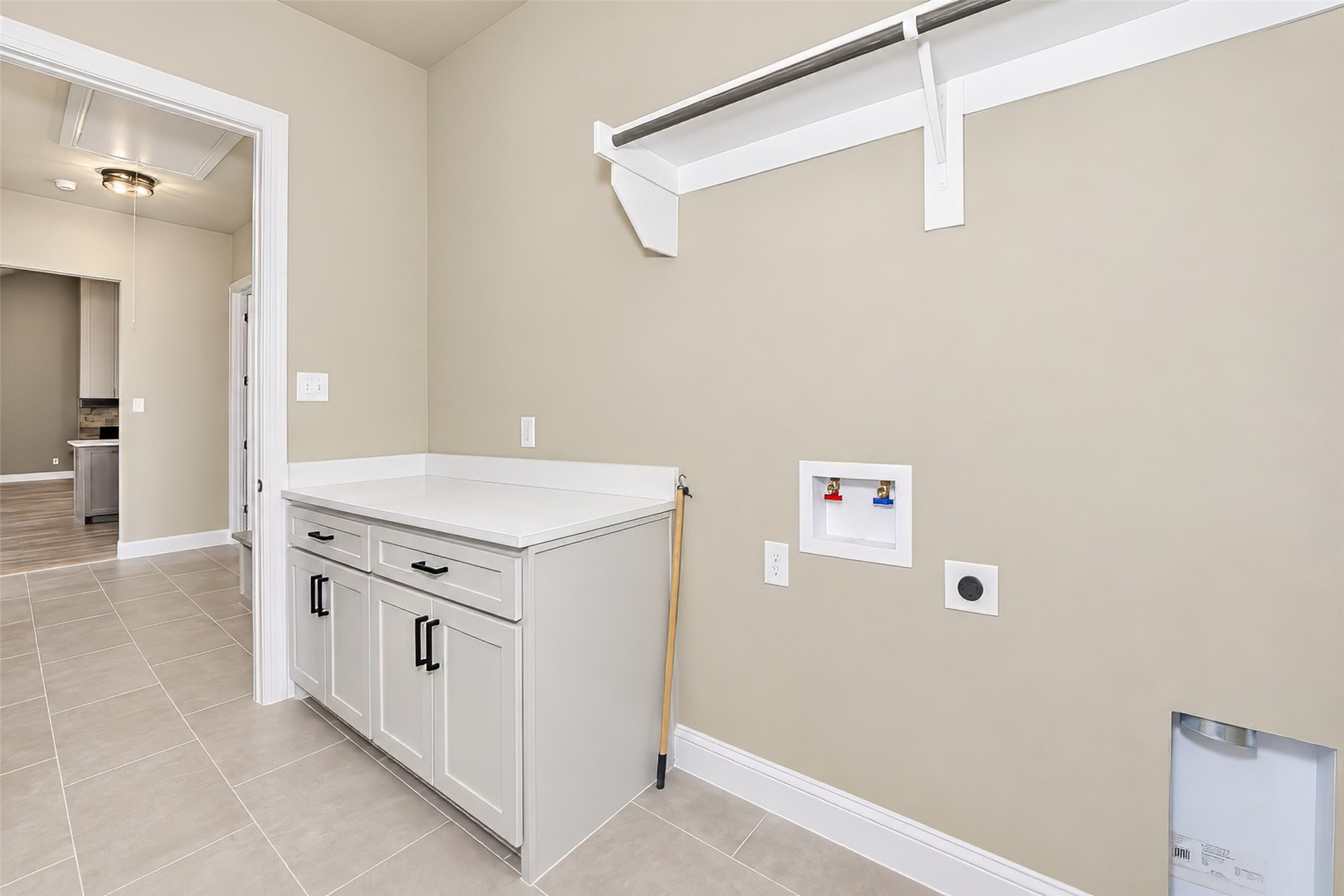 Laundry room with built-in cabinets, a countertop, overhead shelf, and washer hookups.