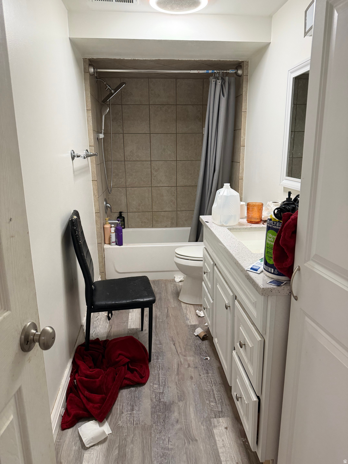 Bathroom with tiled tub and shower, white vanity, and toilet.