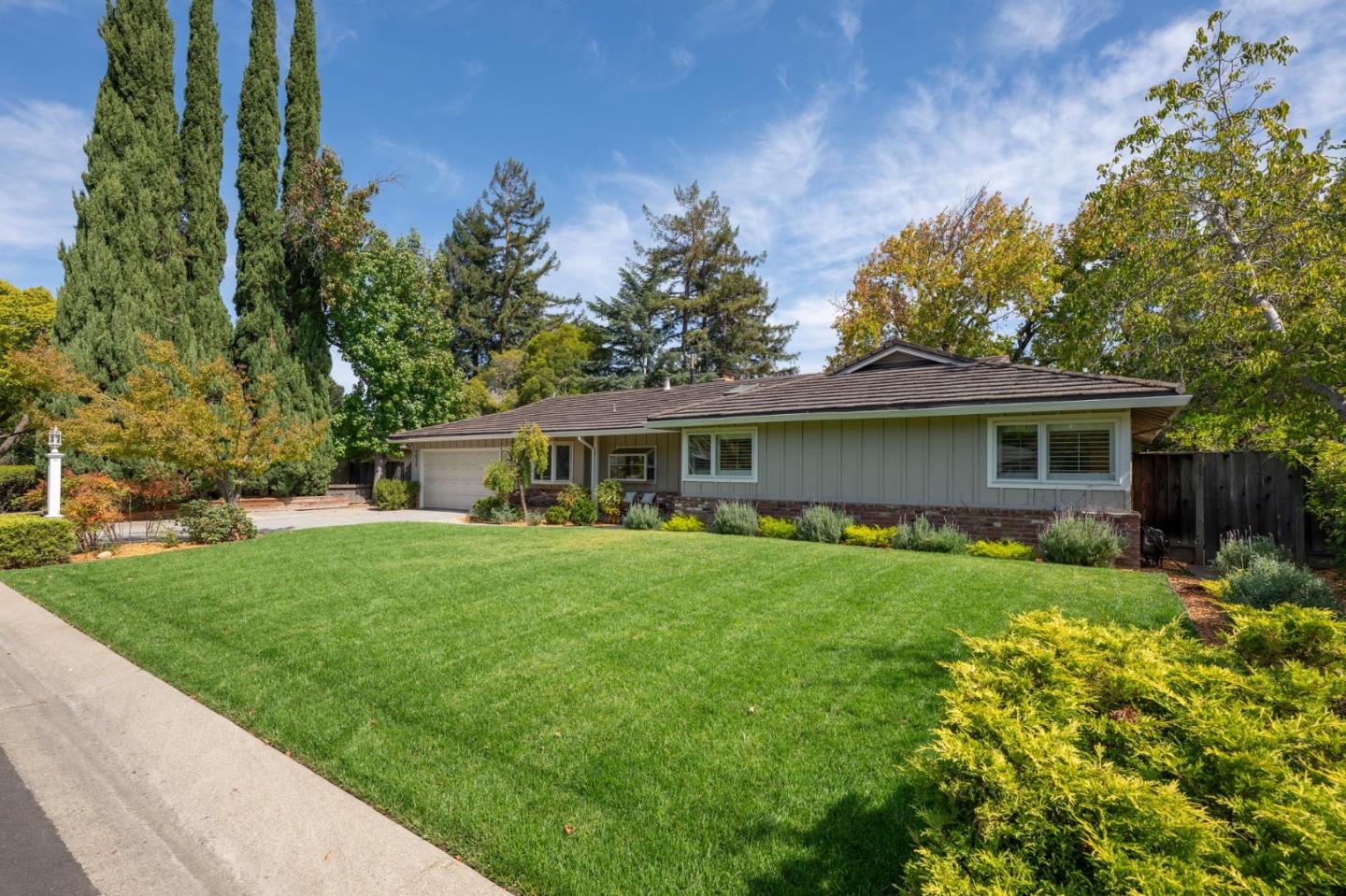 Single-story home with a broad green front lawn, attached garage, and mature trees.