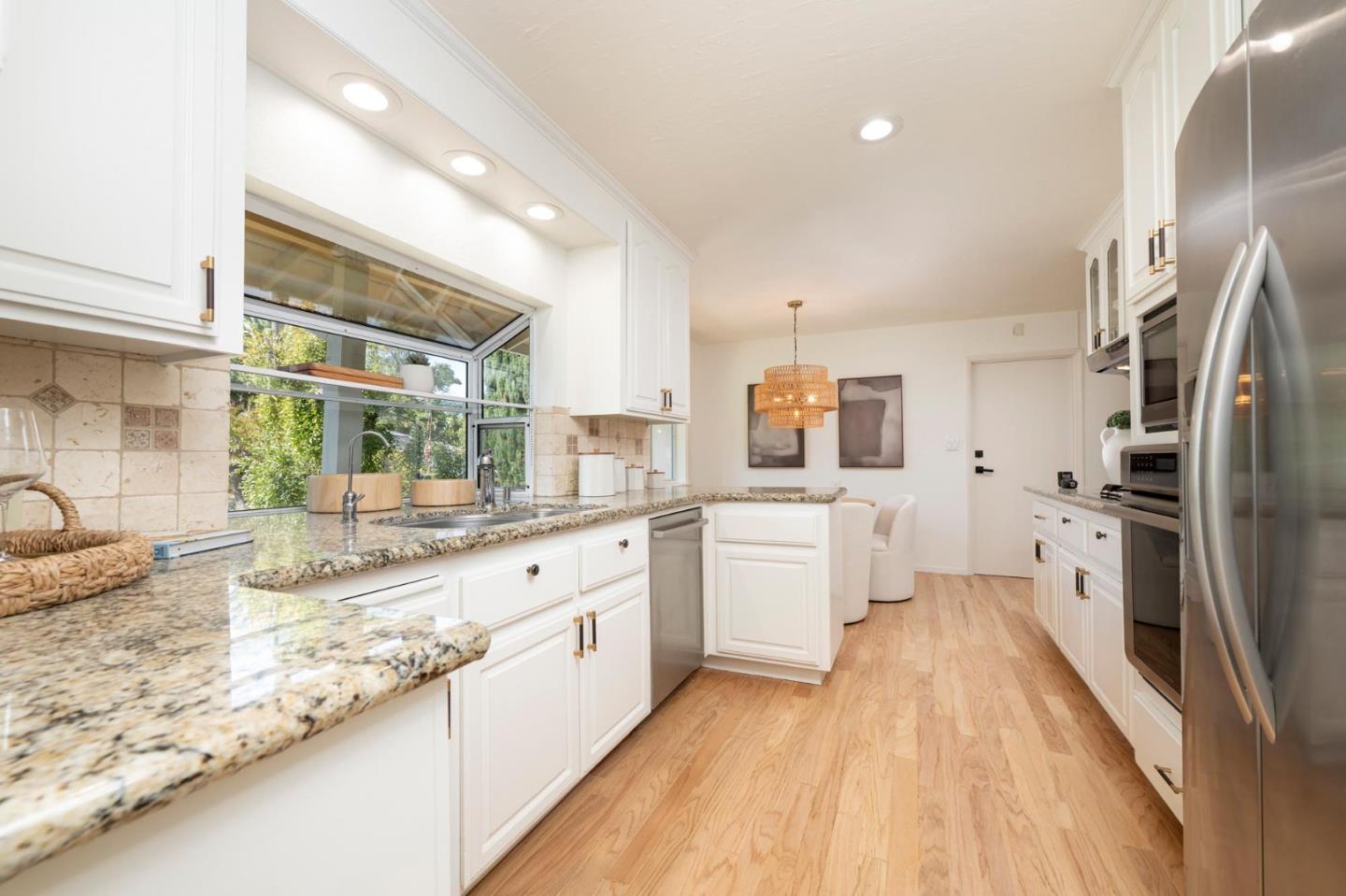 Bright kitchen with granite counters, white cabinets, and a large window above the sink.