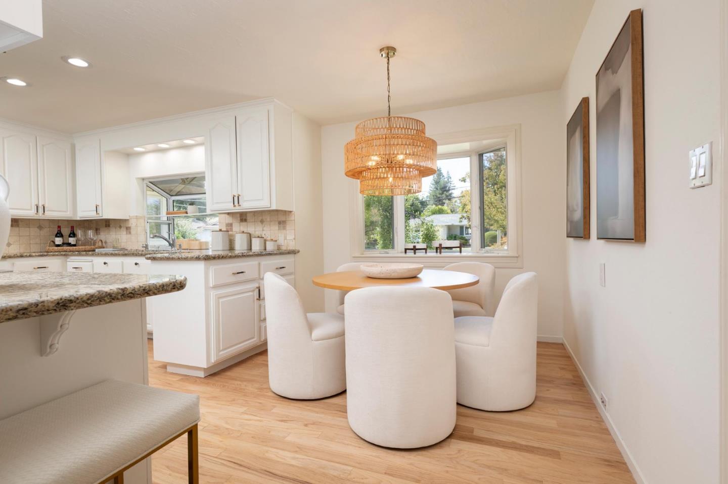 Bright kitchen and dining area with white cabinets, a round table, and woven pendant light.