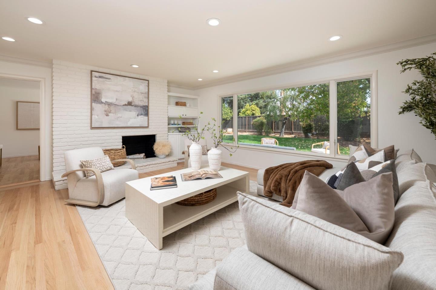 Living room with a white brick fireplace and large window overlooking the backyard.