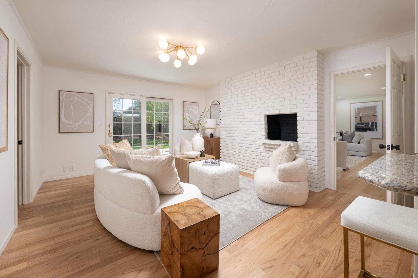 Living room with white seating, a painted brick fireplace, and sliding doors to the garden.
