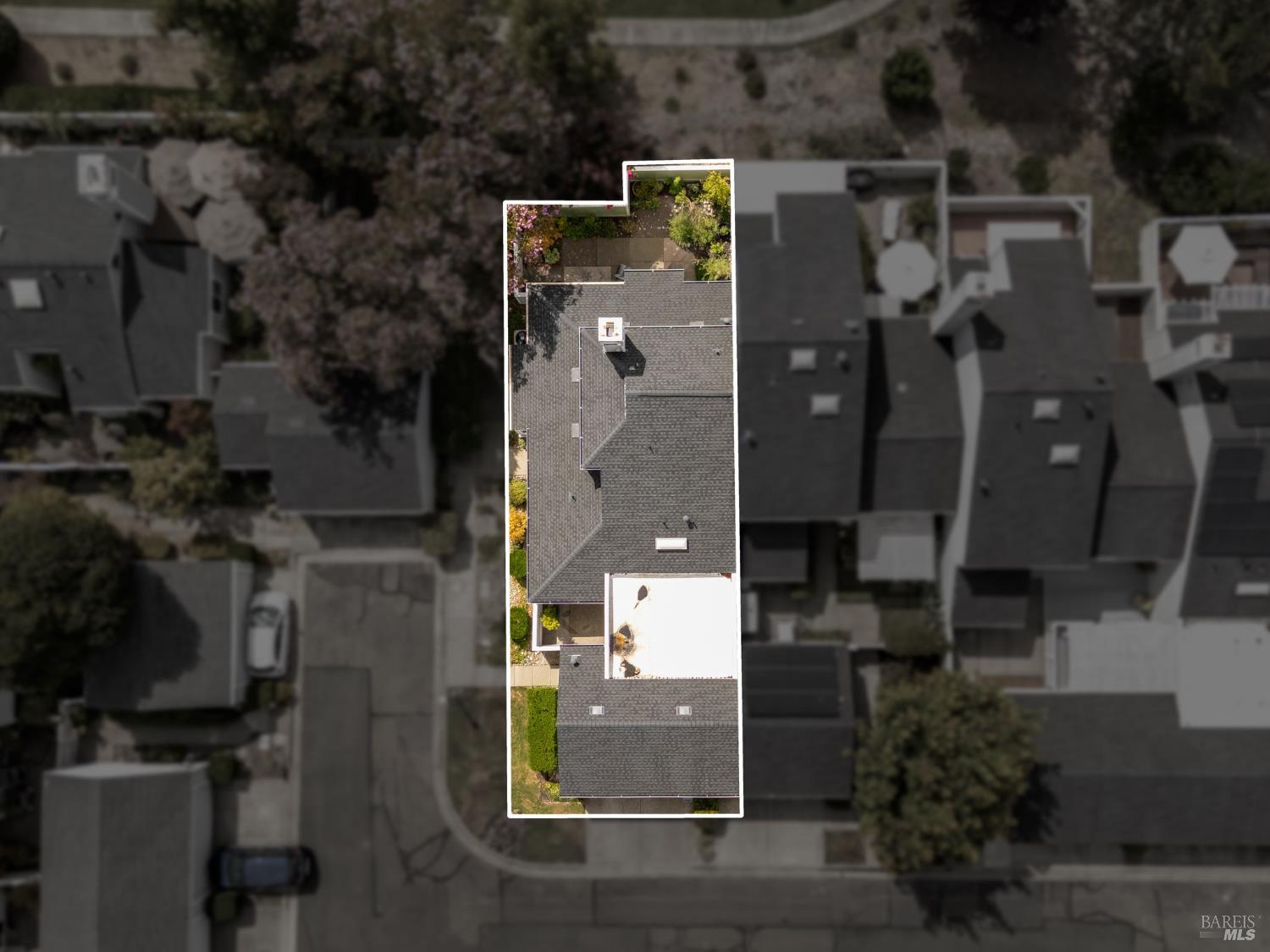 Aerial view of a gray-roofed home outlined in white, with its landscaped backyard visible.