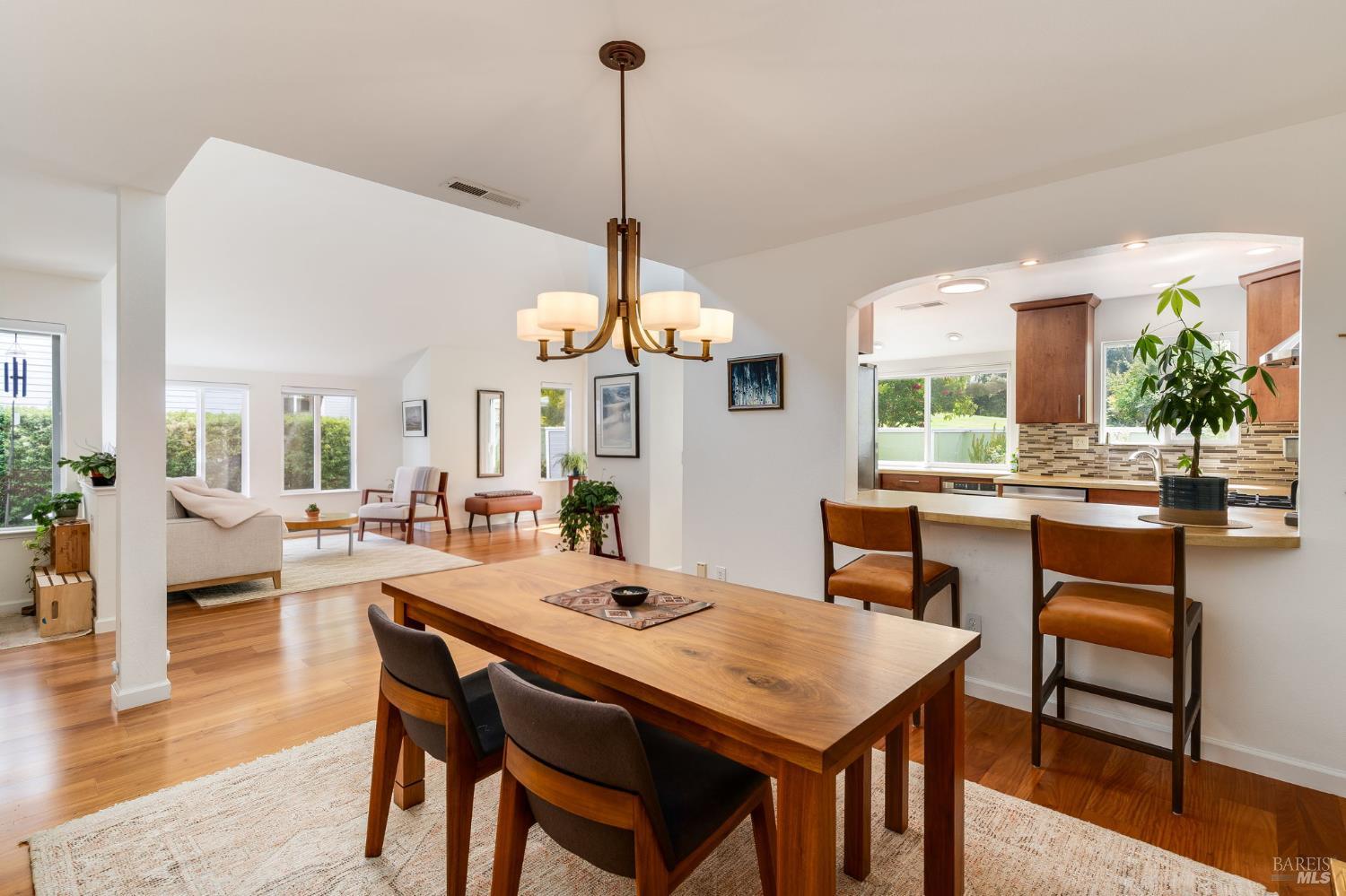 Open-plan dining room, living area, and kitchen with hardwood floors and a large wooden dining table.