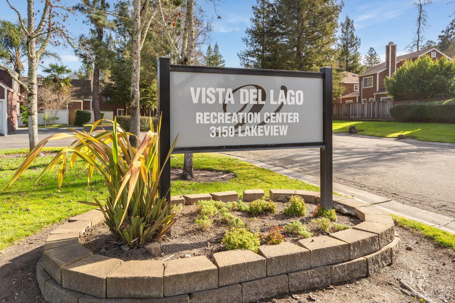 Vista del Lago Recreation Center sign beside landscaped grounds and nearby homes.