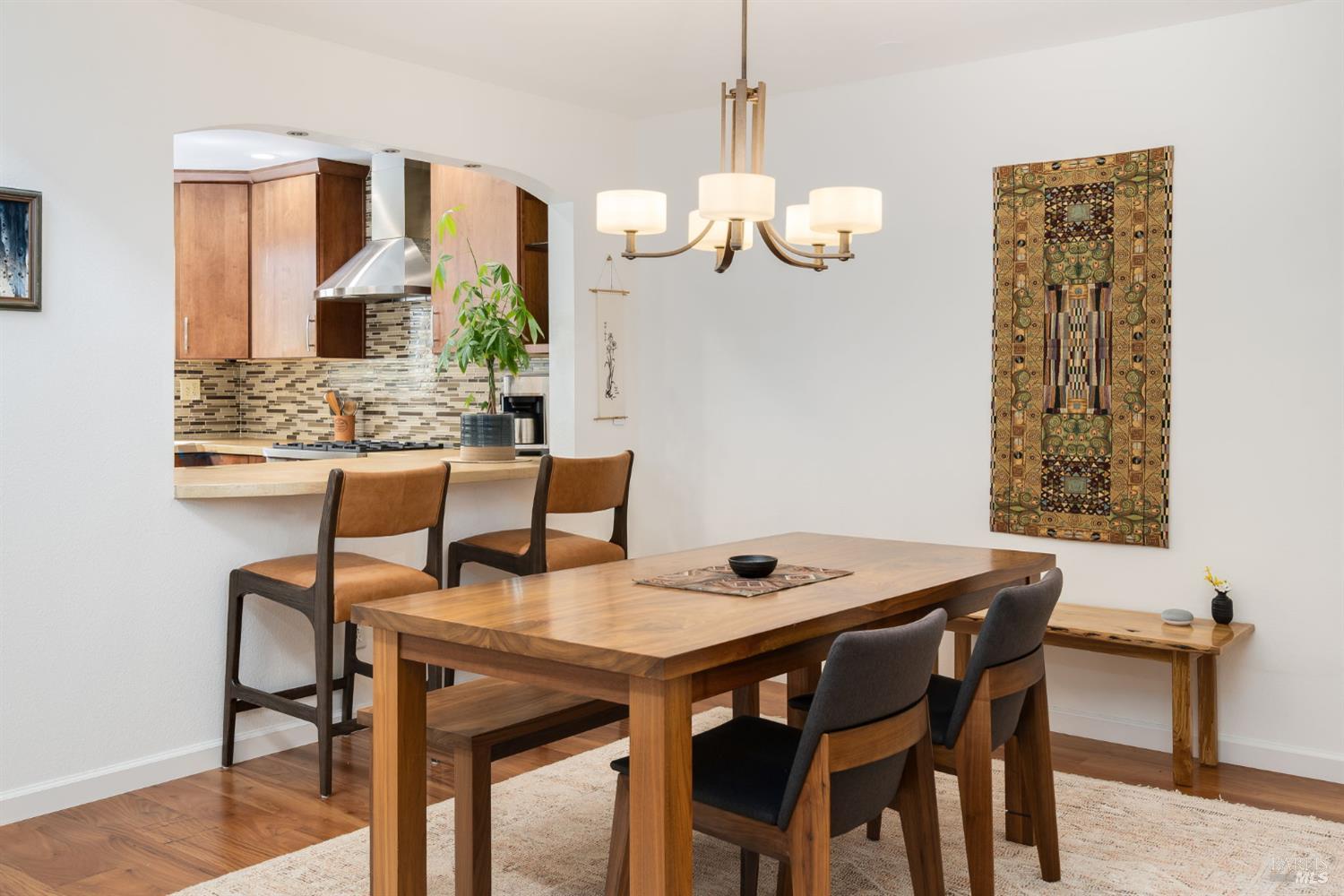 Dining room with a large wood table, chandelier, and an open view into the kitchen.