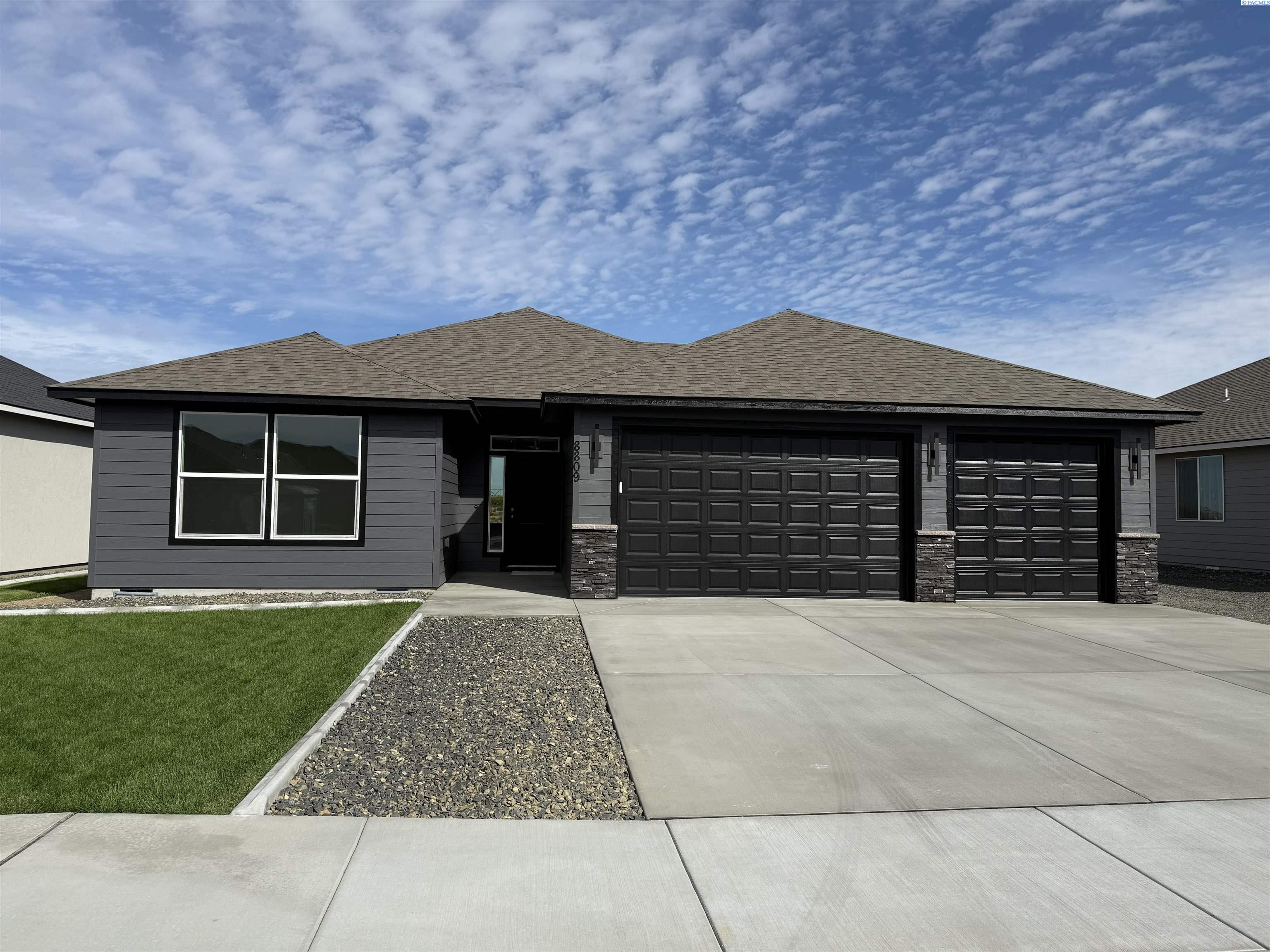 Single-story gray home with two black garage doors, a concrete driveway, and a small front lawn.