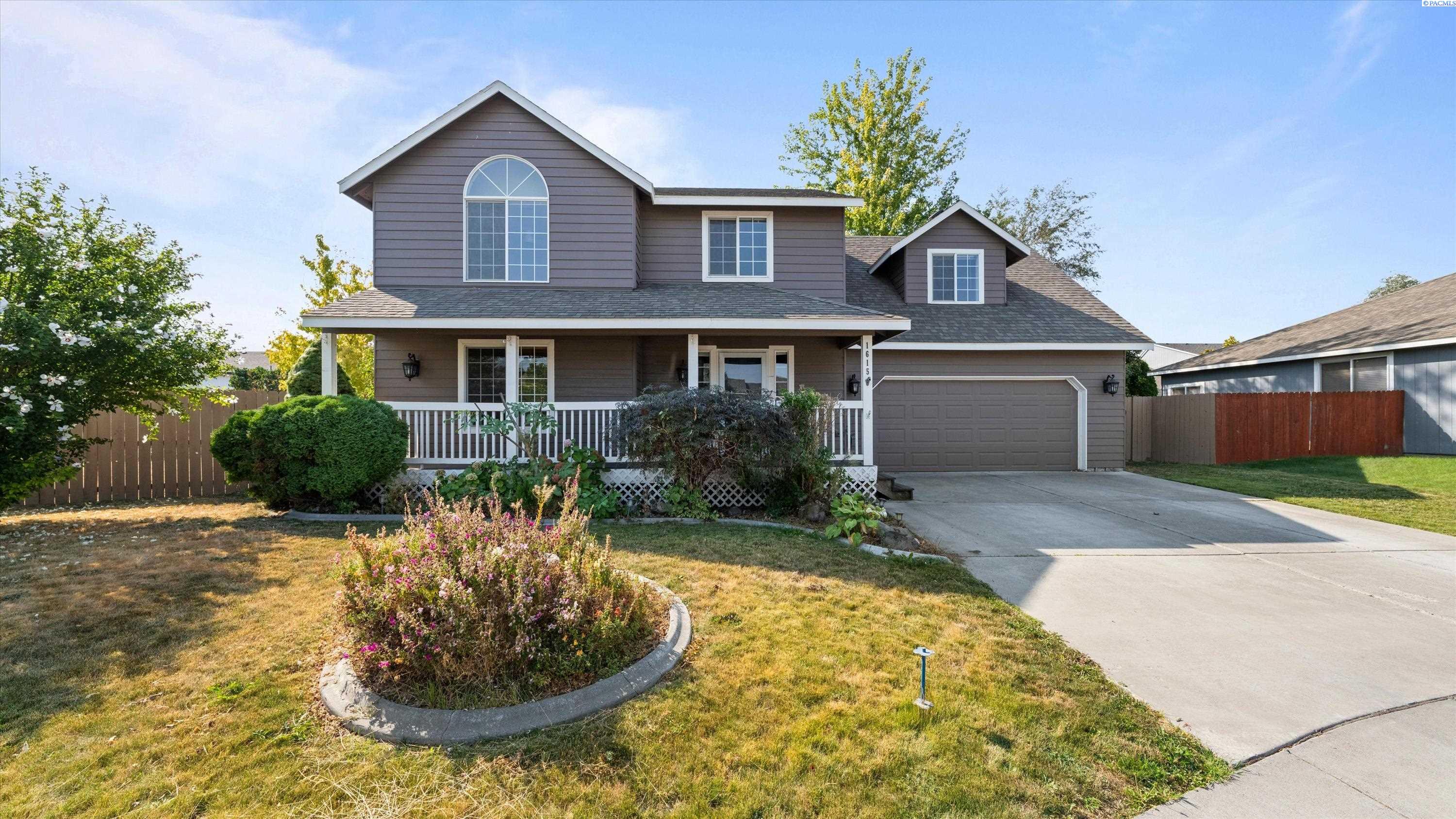 Gray two-story house with an arched upper window, covered porch, attached garage, and landscaped front yard.