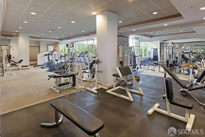 Fitness center with weight machines, exercise benches, treadmills, and large windows.