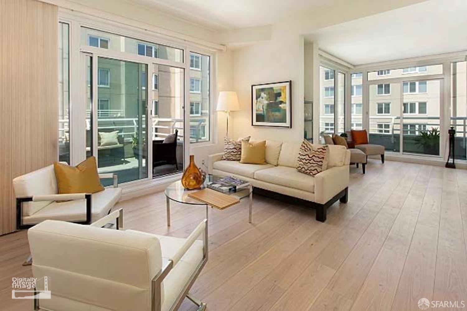 Staged condo living room with cream sofas, pale wood floors, and large windows opening onto balconies.