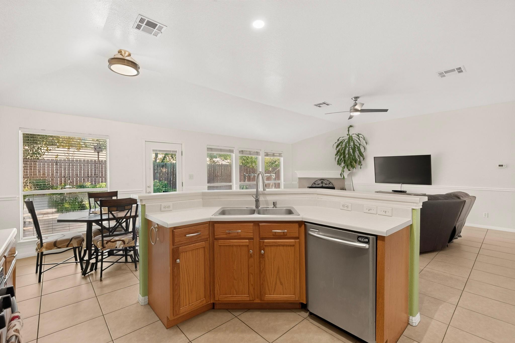 Open kitchen with wood cabinets and a peninsula sink, adjoining a dining area and living room.
