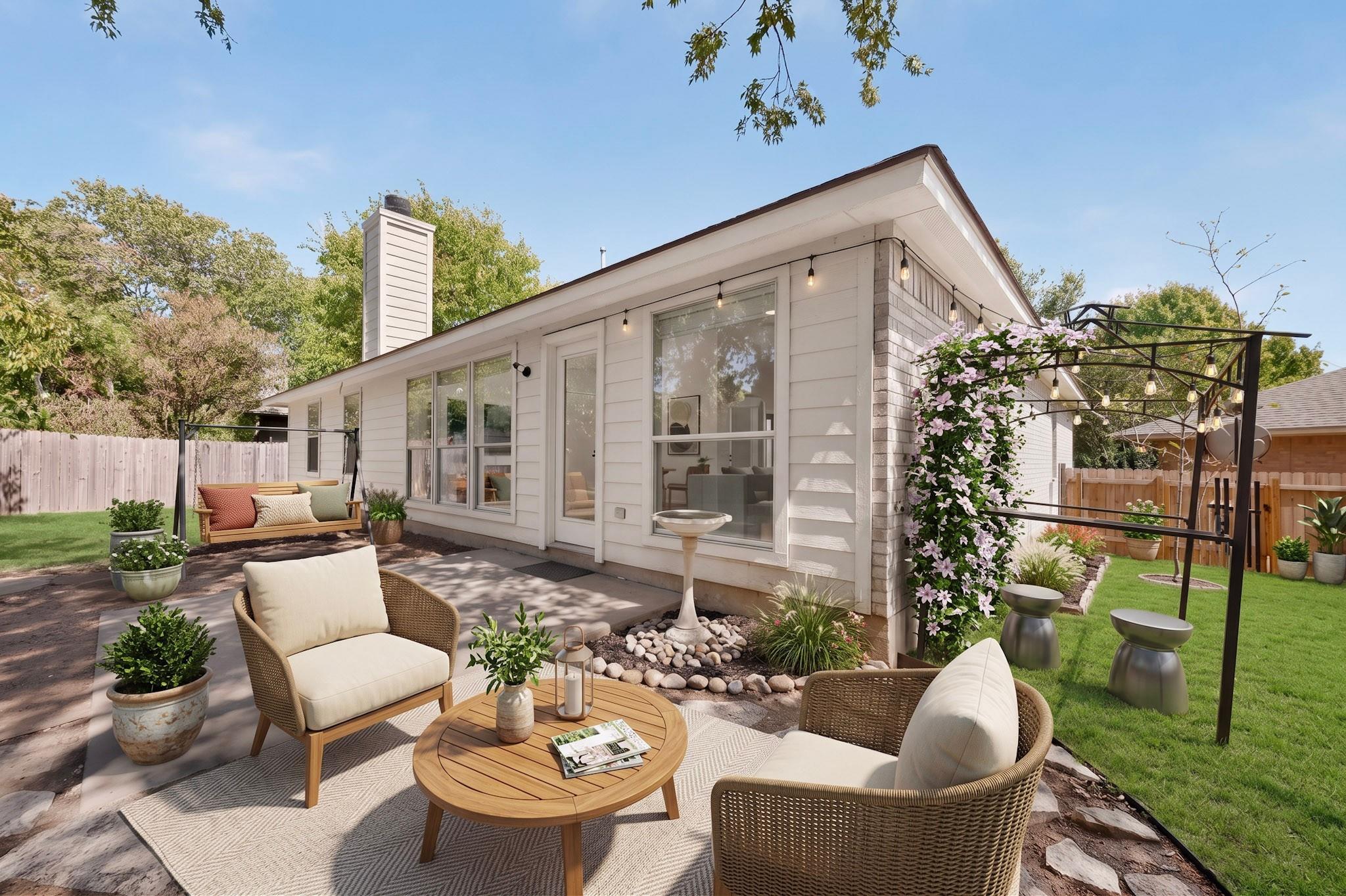 Home’s rear patio with wicker seating, a pergola with string lights, and flowering vines.