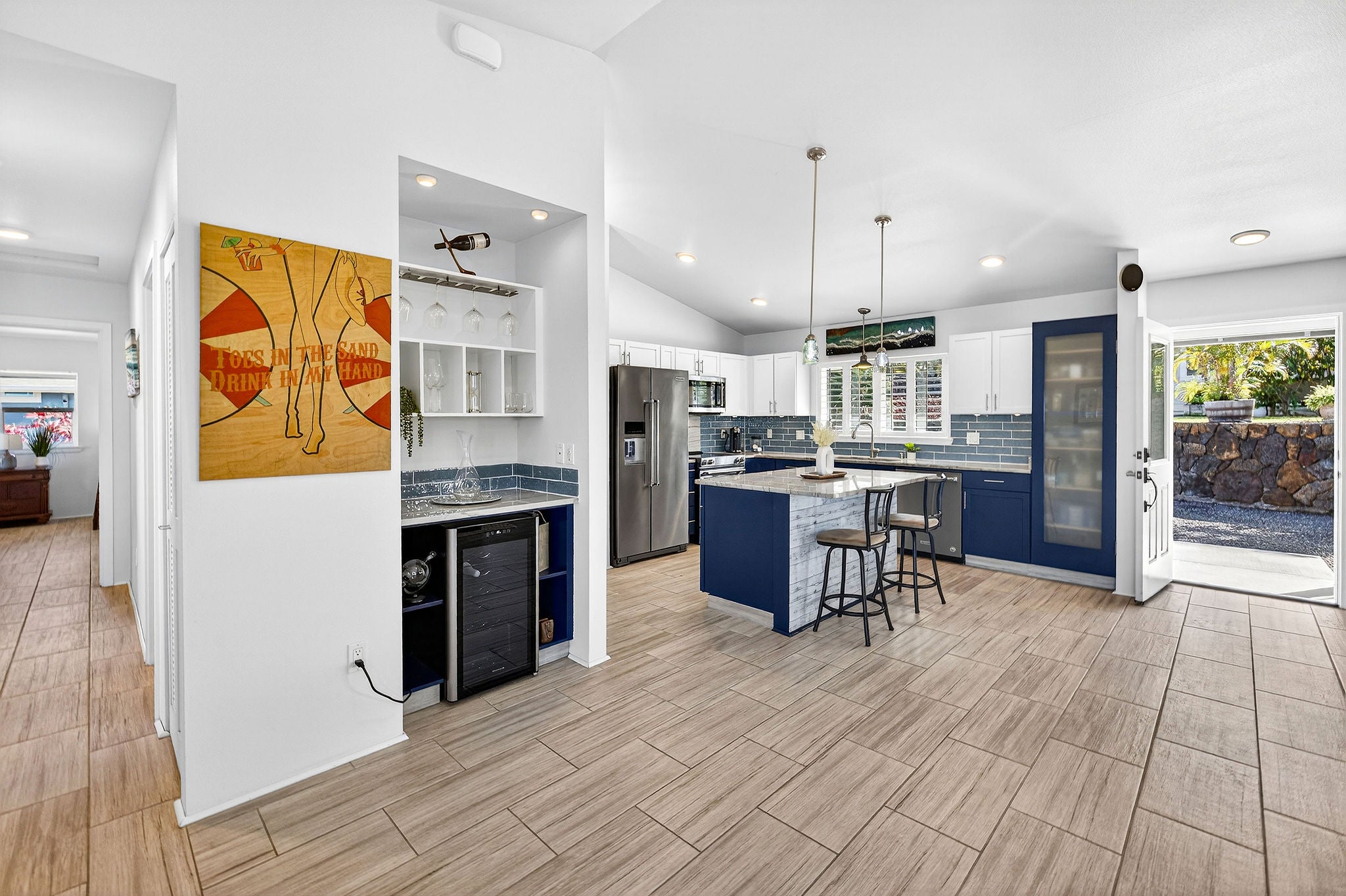 Open kitchen with navy cabinetry, tiled backsplash, island, and wood-look tile floors.