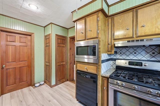 Kitchen with wood cabinets, stainless steel appliances, and a blue-and-white tile backsplash.