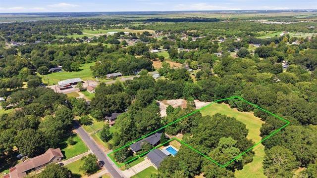 Aerial view of a wooded property outlined in green, with a house, pool, and open grassy areas.