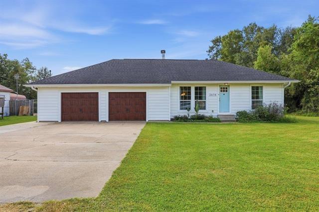 Single-story white house with two brown garage doors, a pale blue front door, and a wide driveway.