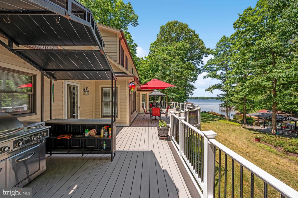 Lakeside home deck with a covered grill station and red-umbrella dining area overlooking the water.