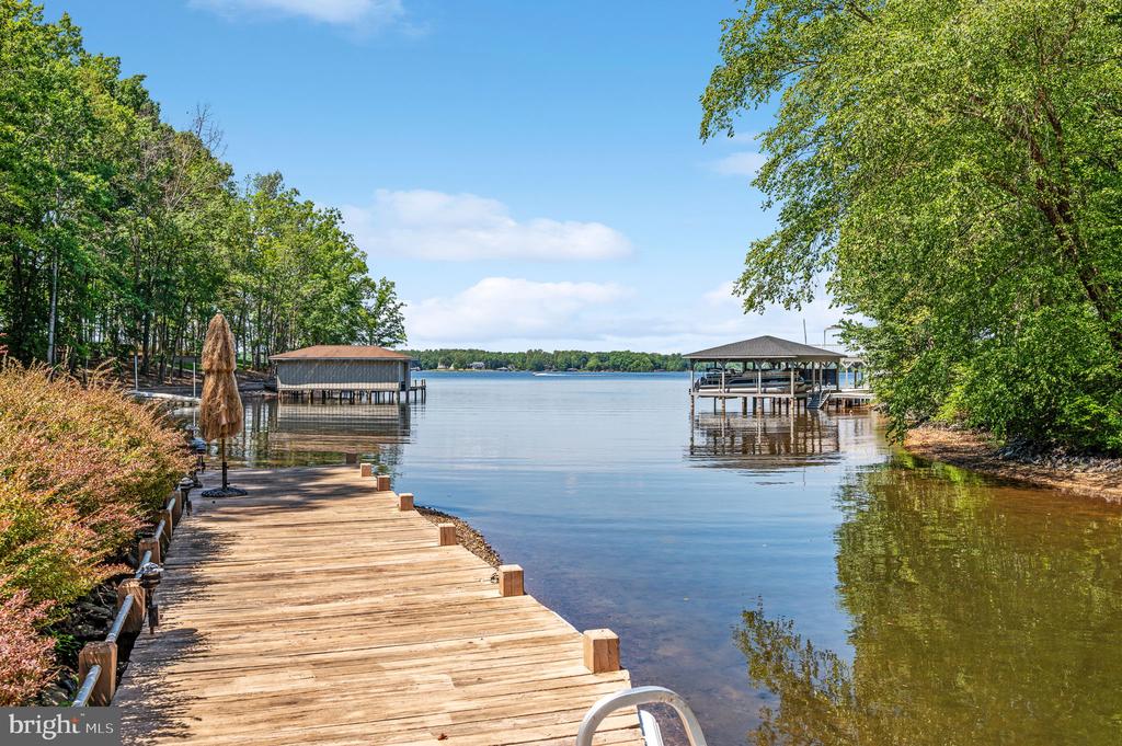 Wooden dock curves along a calm lake toward covered boat docks.
