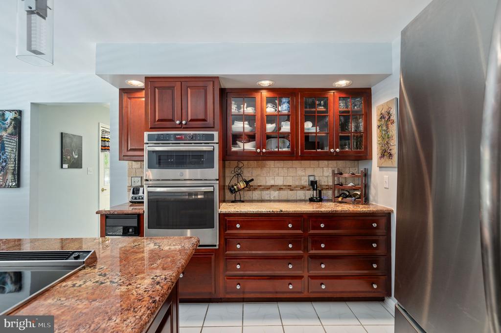 Kitchen with cherry cabinets, a stainless double wall oven, and granite counters and island.