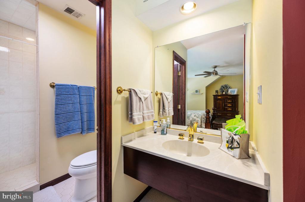 Bathroom with a white vanity, large mirror, tiled shower, and blue towels.
