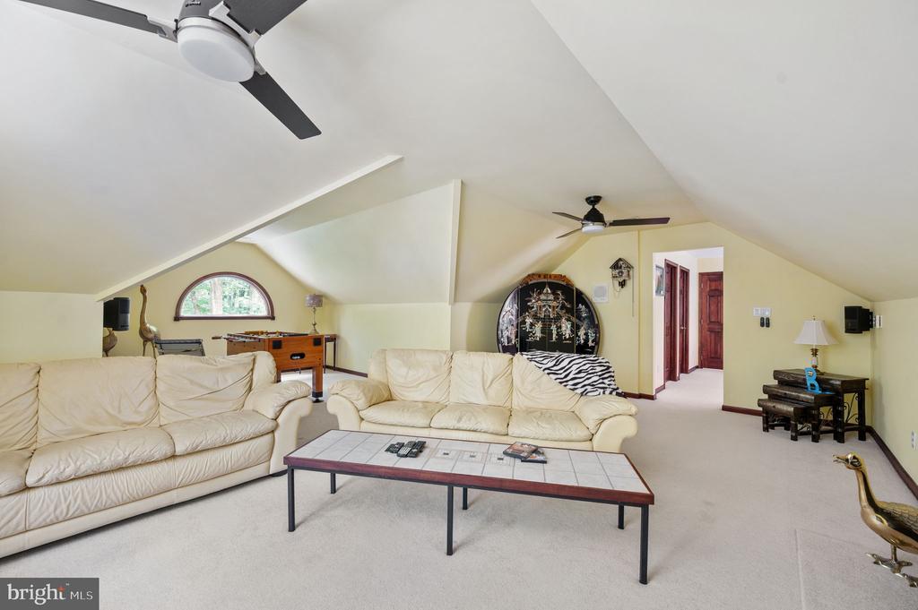 Upstairs recreation room with cream leather sofas, foosball table, and sloped ceilings.