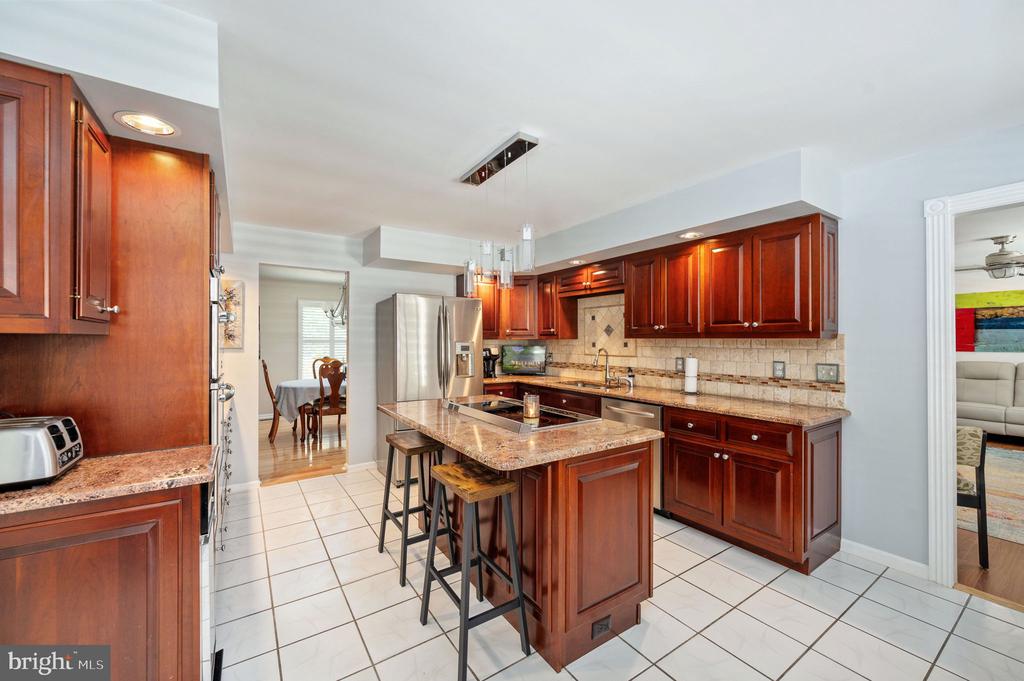 Kitchen with dark wood cabinets, granite counters, and a central island with seating.