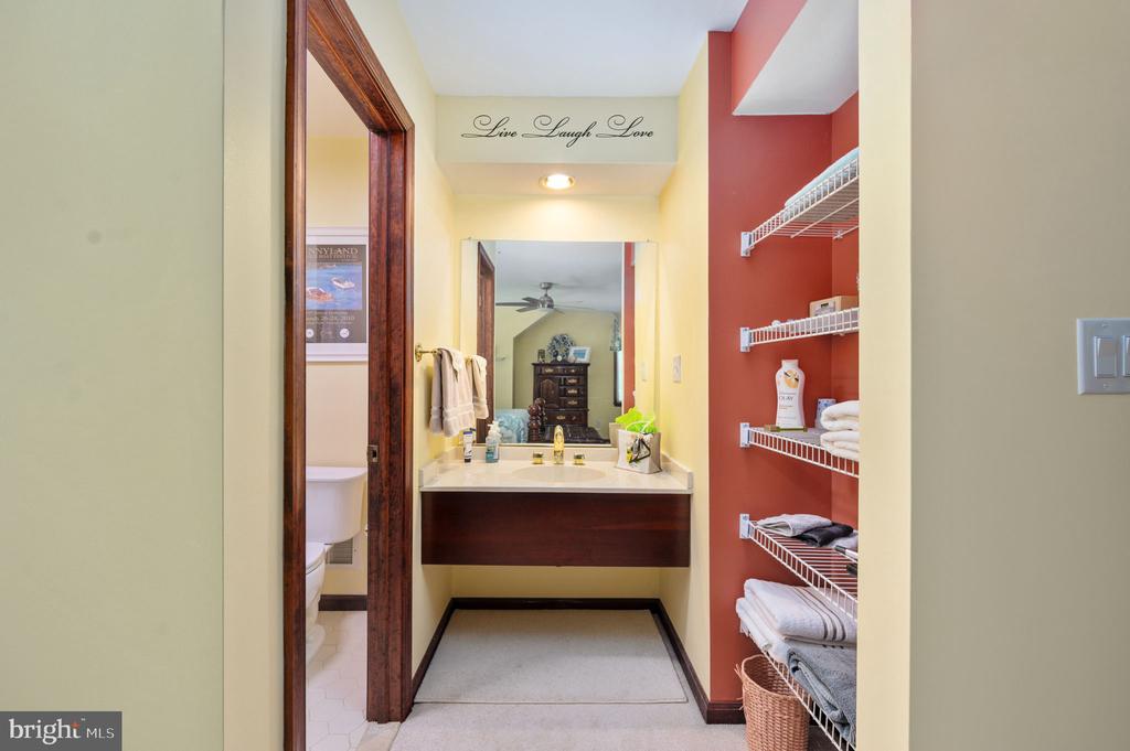 Bathroom vanity with a wide mirror, dark wood cabinet, and open shelves holding folded towels.