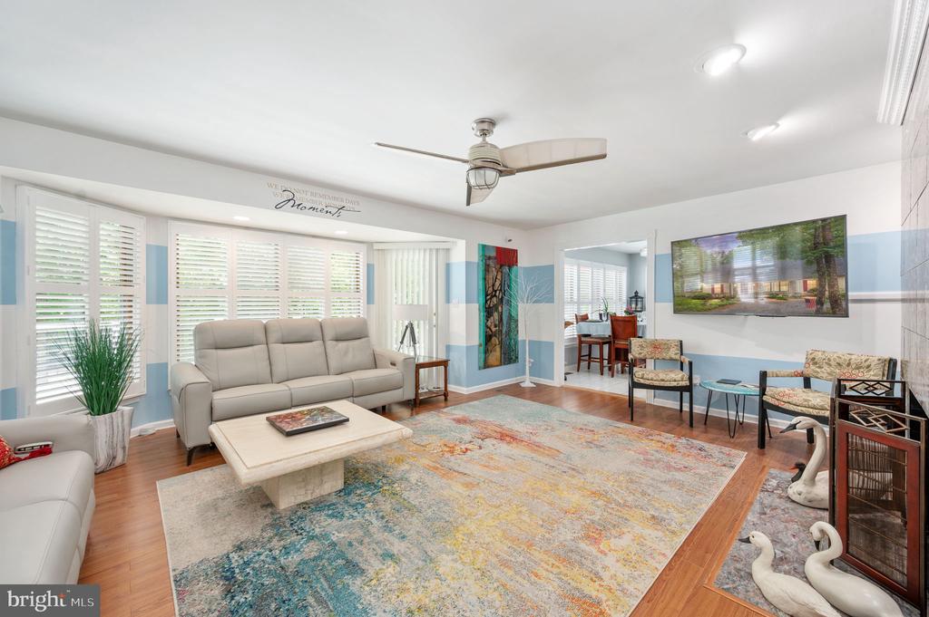 Furnished living room with plantation shutters, a beige sofa, and a colorful rug.